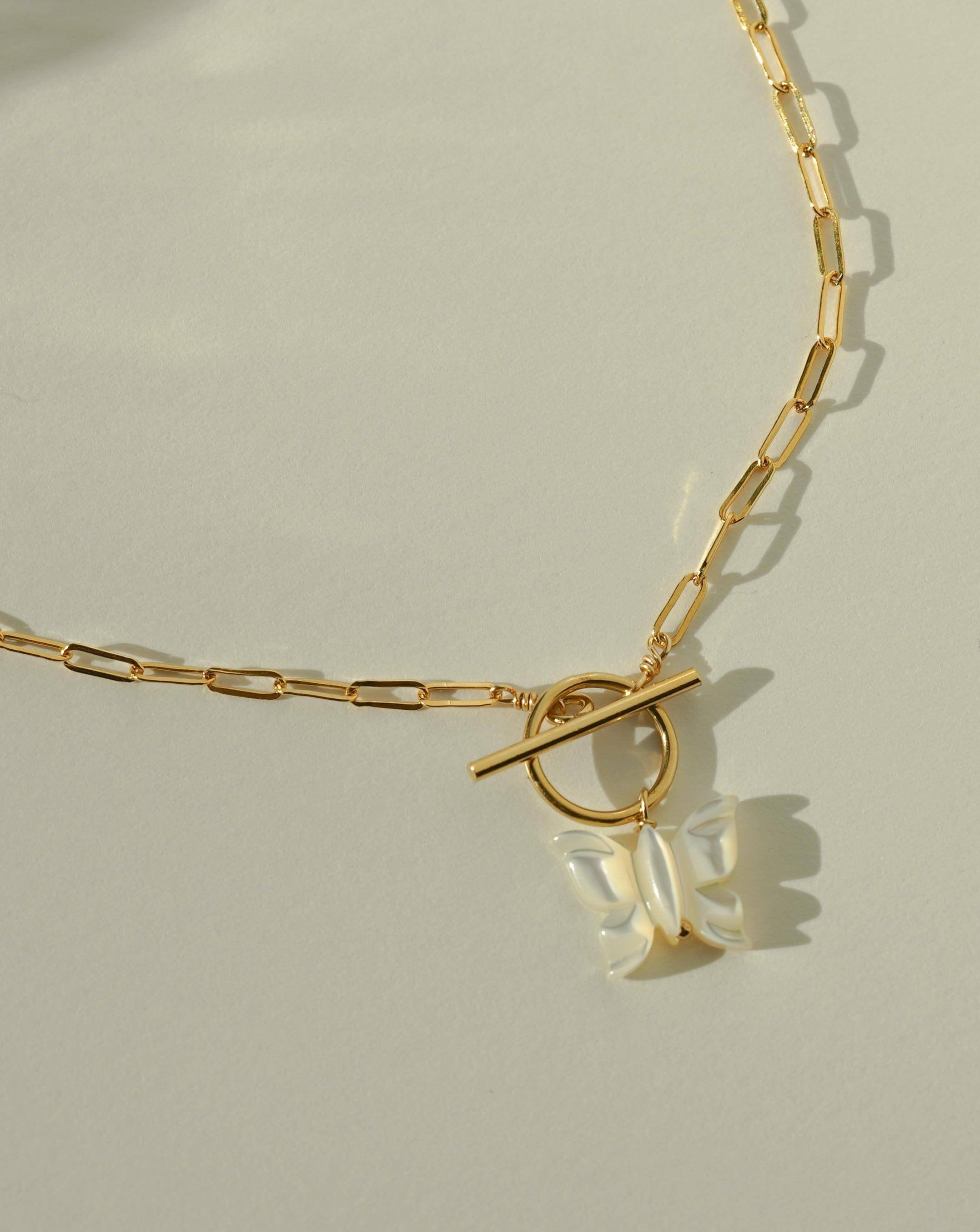 Arlette Necklace by KOZAKH. A 16 to 18 inch adjustable length necklace in 14K Gold Filled, featuring a hand-carved Mother of Pearl butterfly charm and a toggle closure at front of the necklace.