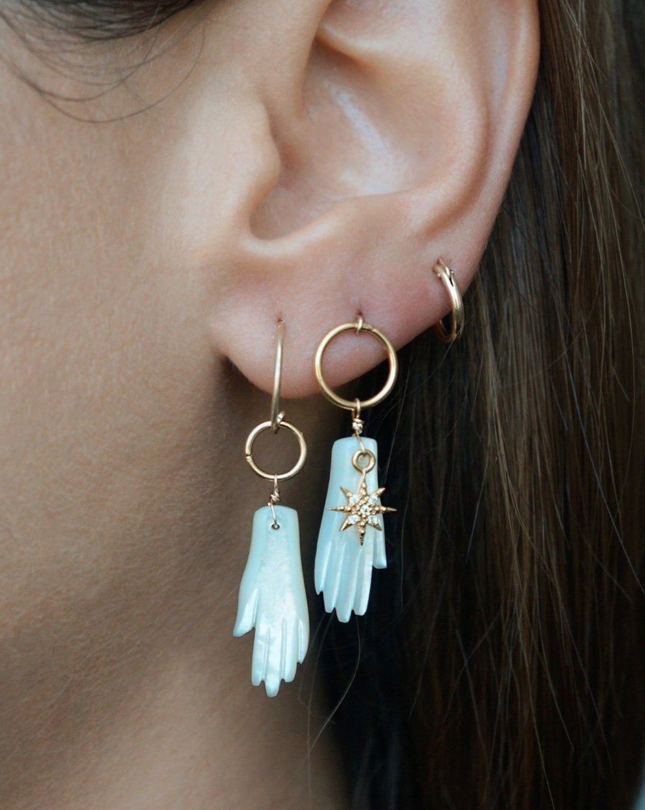 Astra Earrings by KOZAKH. Dangling earrings in 14K Gold Filled, featuring a hand carved Mother of Pearl hand charm and a Cubic Zirconia star charm.