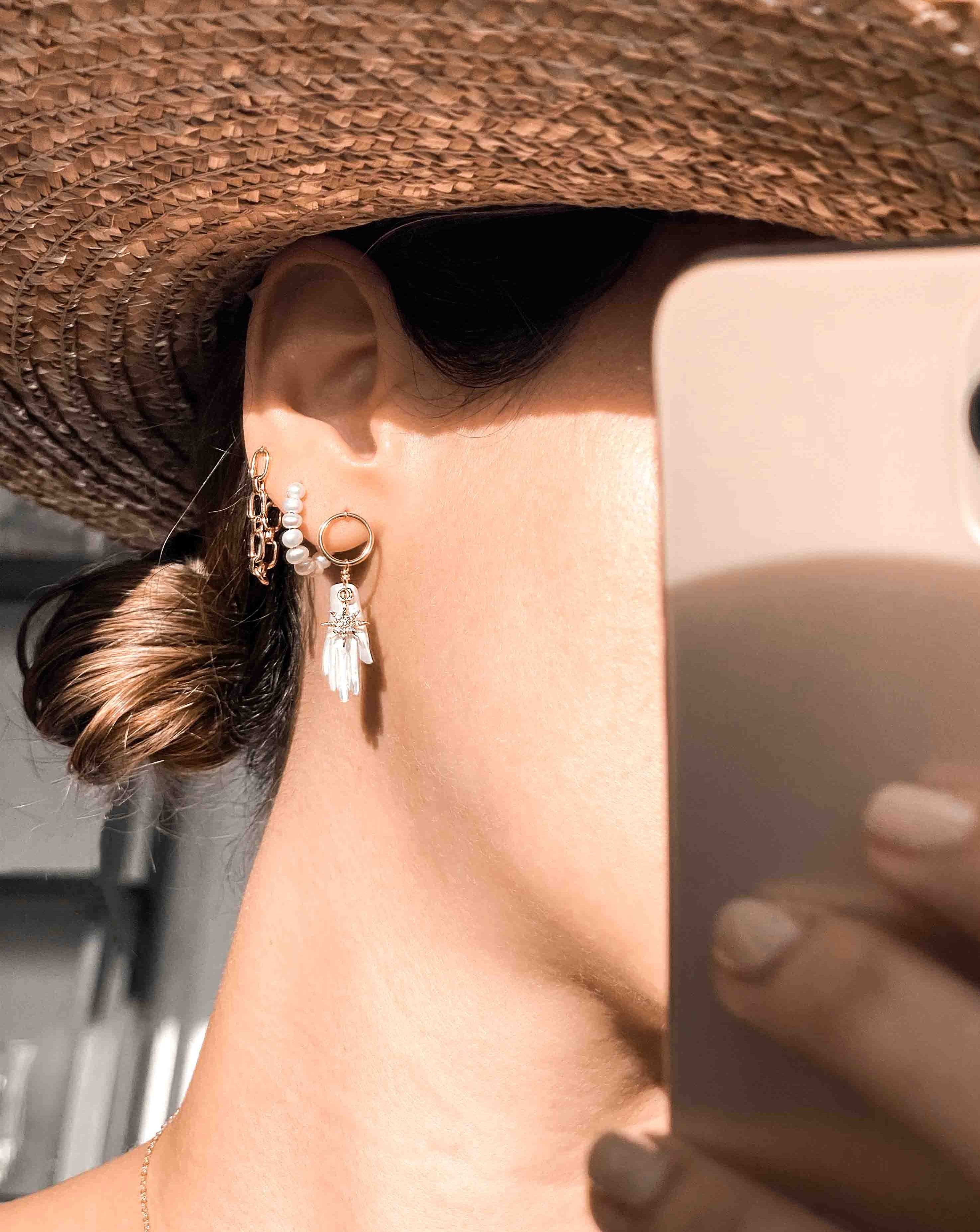 Astra Earrings by KOZAKH. Dangling earrings in 14K Gold Filled, featuring a hand carved Mother of Pearl hand charm and a Cubic Zirconia star charm.