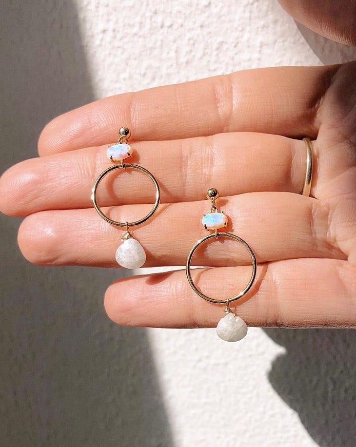 Azuu Earrings by KOZAKH. A 1 1/2 inch dangling earrings in 14K Gold Filled, featuring an Opal charm and a faceted White Sapphire.
