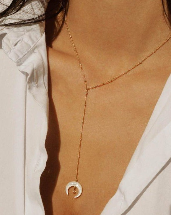 Baque Lar Necklace by KOZAKH. A 16 to 18 inch adjustable length, 3 inches chain drop lariat style necklace in 14K Gold Filled, featuring a hand-carved Mother of Pearl moon charm and a 2mm Swarovski Crystal.