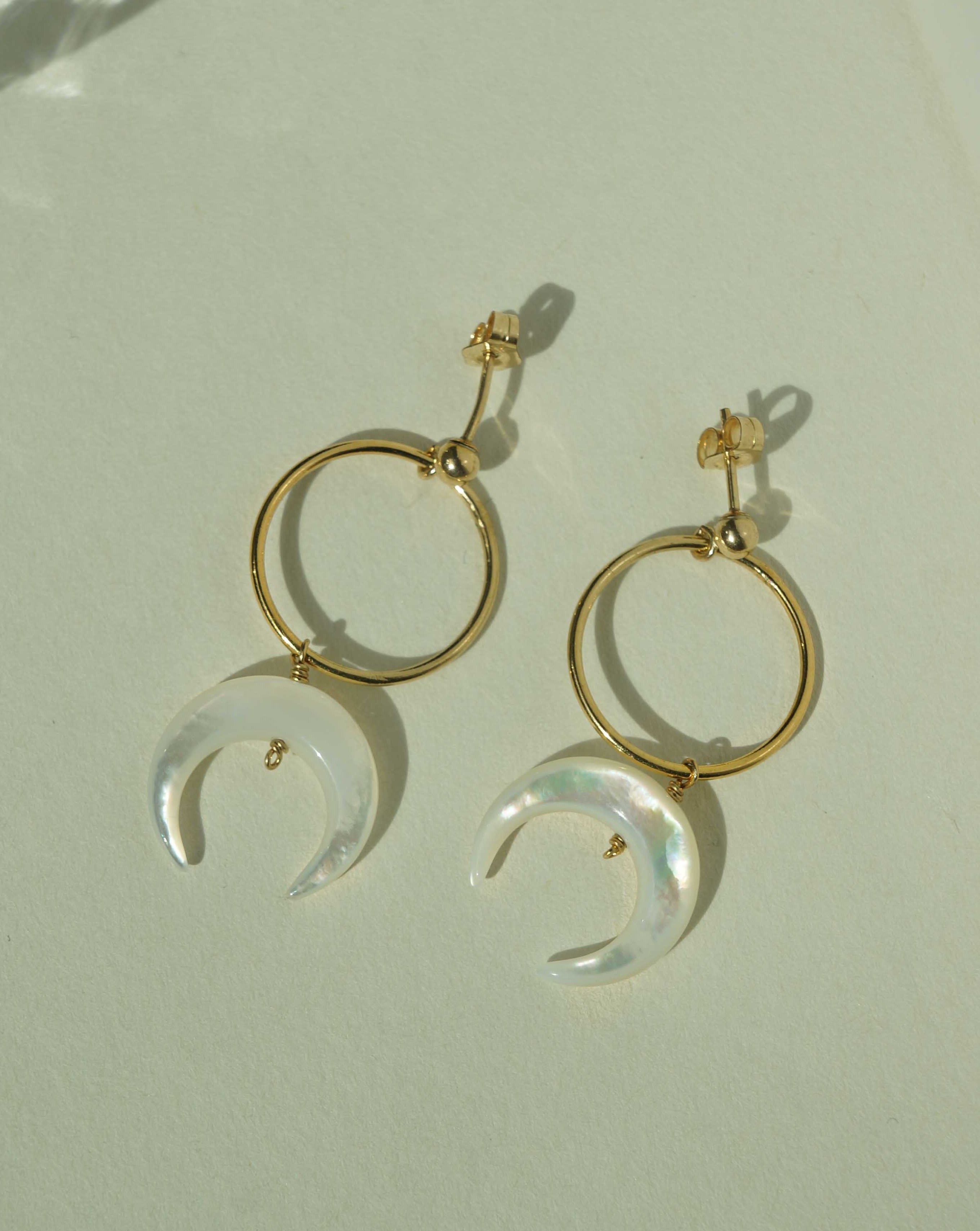 Baques Earrings by KOZAKH. Dangling earrings in 14K Gold Filled, featuring a hand-carved Mother of Pearl moon charm.