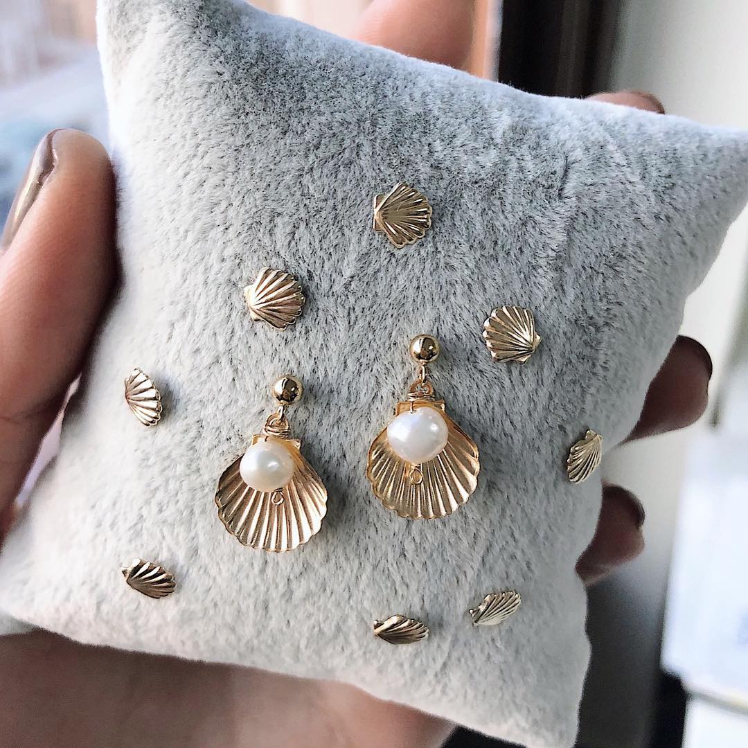 Belle Earrings by KOZAKH. Dangling earrings in 14K Gold Filled, featuring a 5mm flat irregular Pearl and a Shell charm.