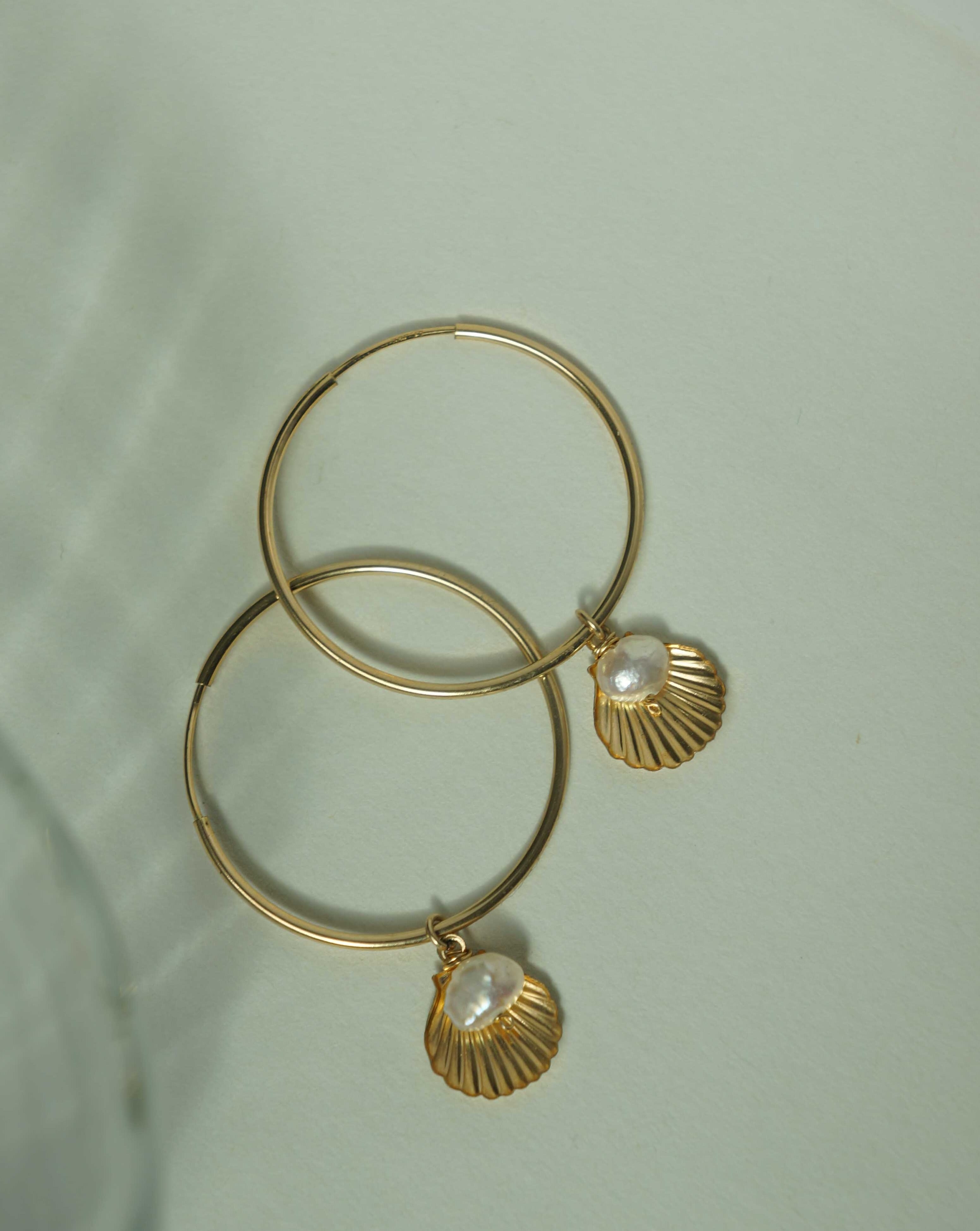 Belle Hoop Earrings by KOZAKH. A 30mm hoop earrings in 14K Gold Filled, featuring a 5mm flat irregular Pearl and a Shell charm.