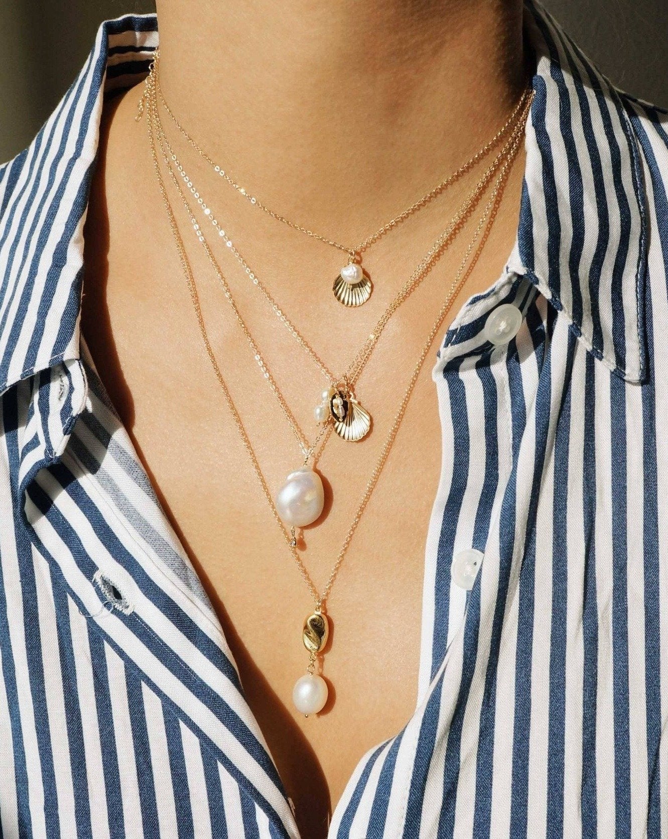 Belle Necklace by KOZAKH. A 16 to 18 inch adjustable length necklace in 14K Gold Filled, featuring a 5mm flat irregular Pearl and a Shell charm.