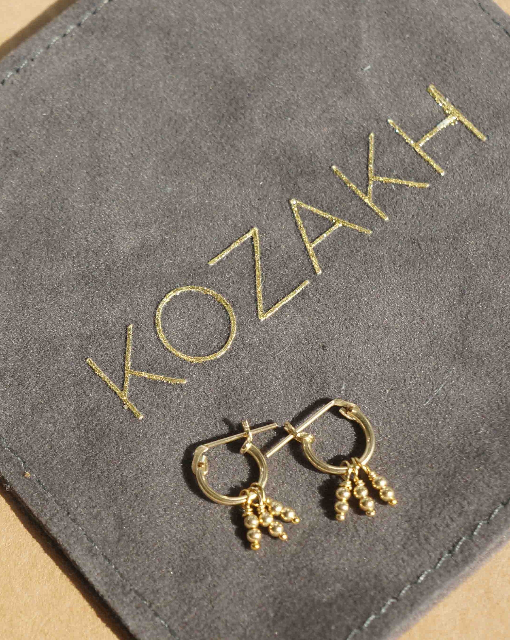 Daphne Hoop Earrings by Kozakh. 10mm Snap closure hoops crafted in 14K Gold Filled, featuring dangling gold balls.