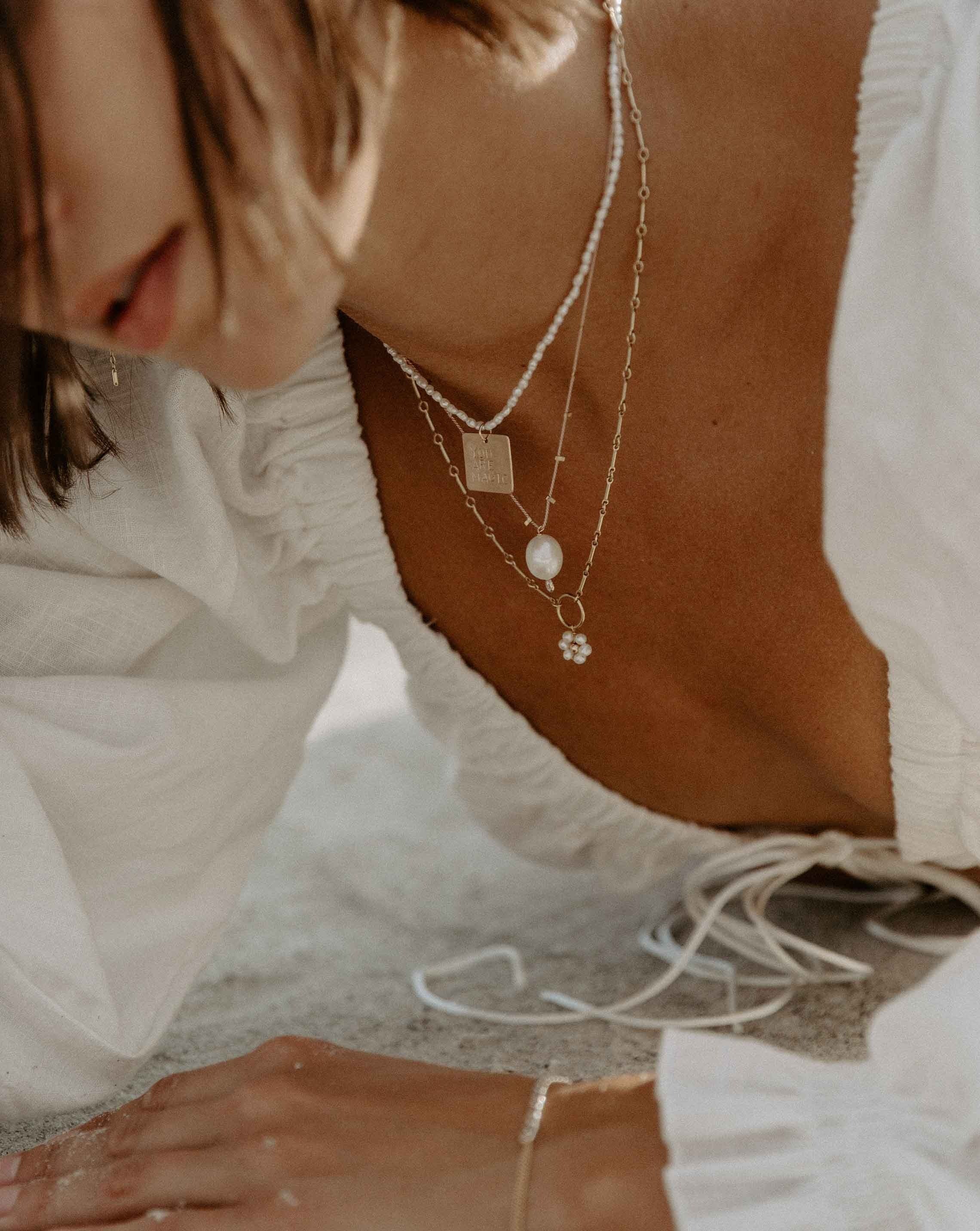 Flor Del Sol Necklace by KOZAKH. A 16 to 18 inch adjustable length necklace in 14K Gold Filled, featuring 3mm Freshwater Pearls in form of a daisy.