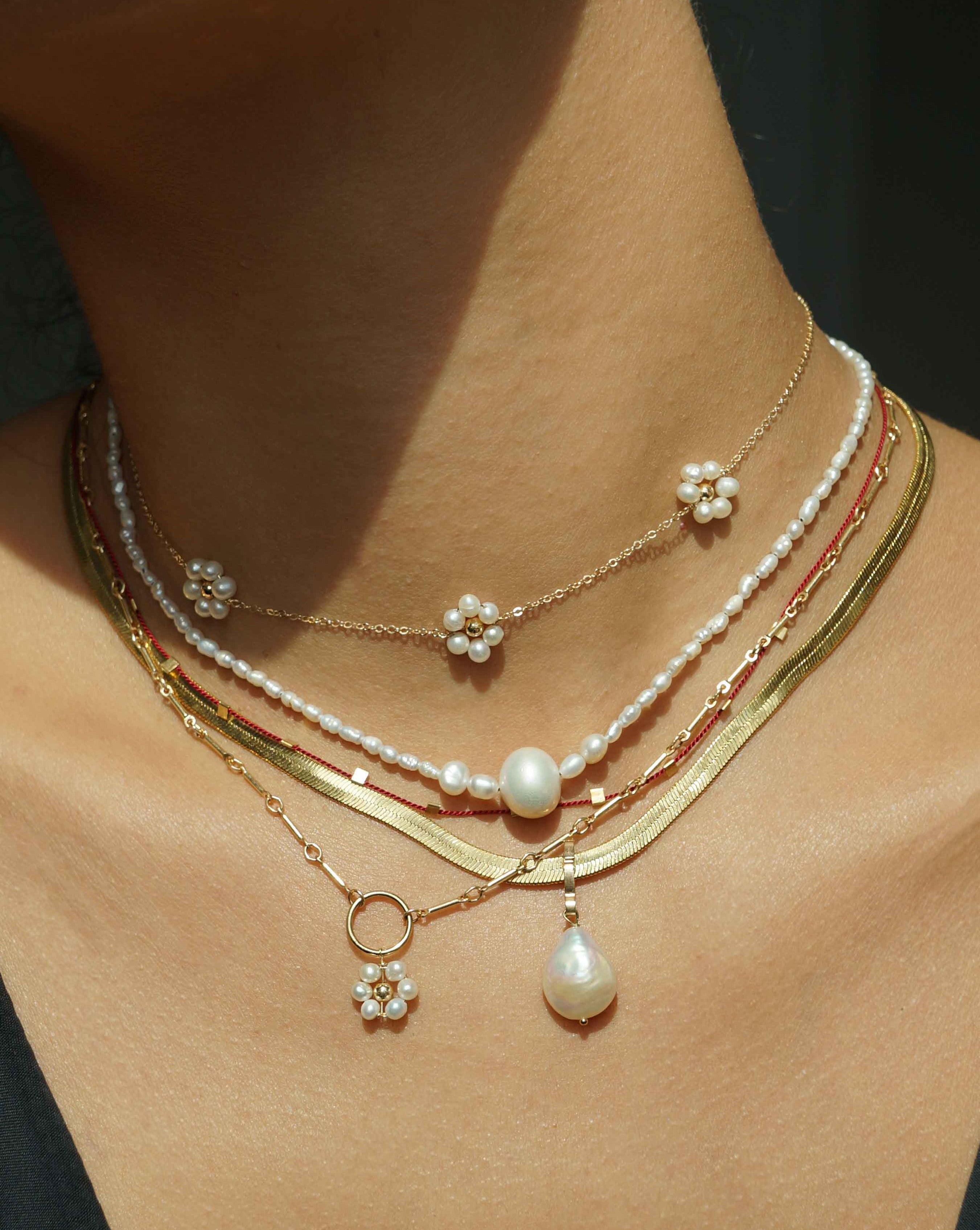 Flor Del Sol Necklace by KOZAKH. A 16 to 18 inch adjustable length necklace in 14K Gold Filled, featuring 3mm Freshwater Pearls in form of a daisy.