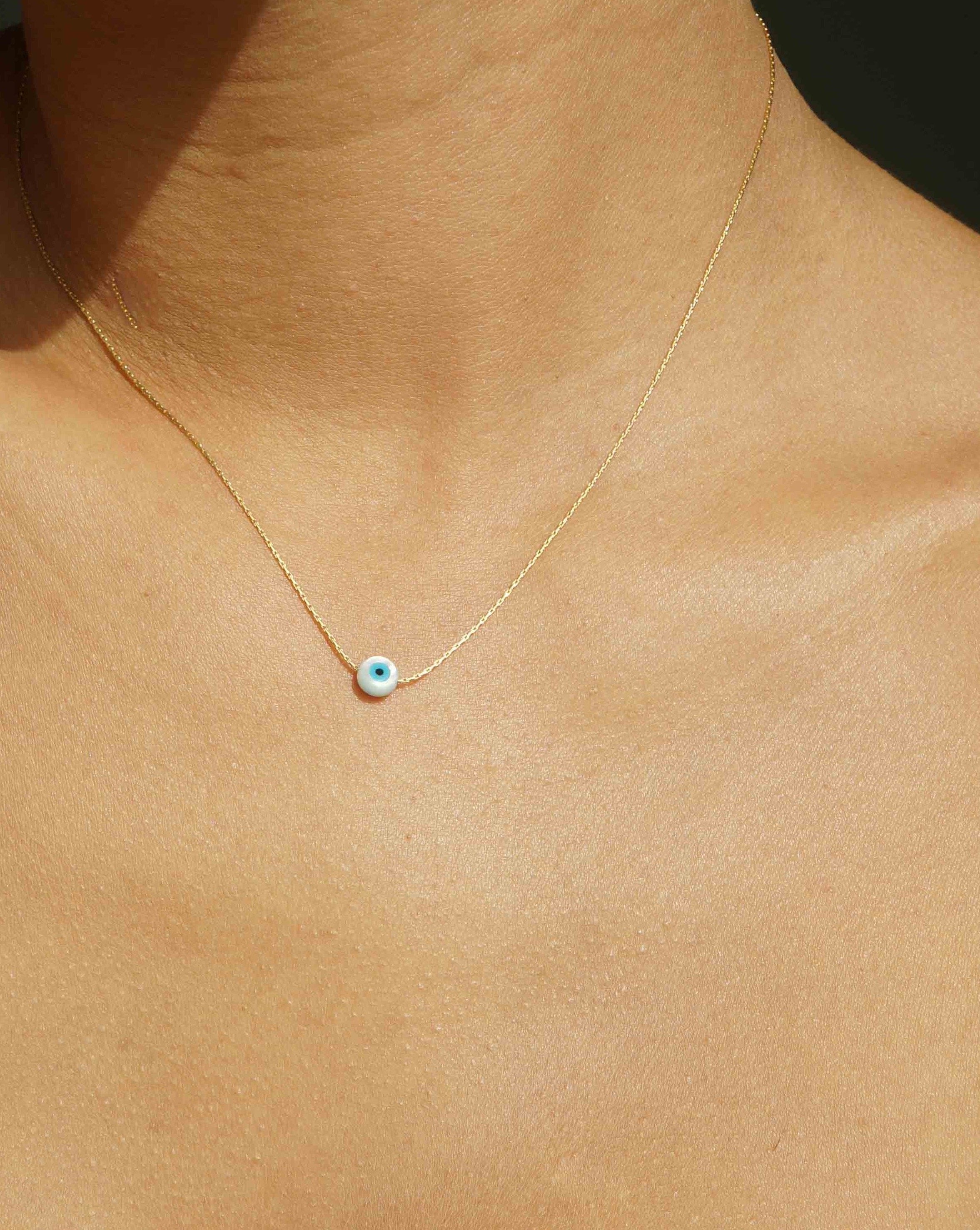 Idra Necklace by KOZAKH. A 16 to 18 inch adjustable length, 1mm thick cordette chain necklace in 14K Gold Filled, featuring a 5mm hand carved Mother of Pearl Evil Eye charm.