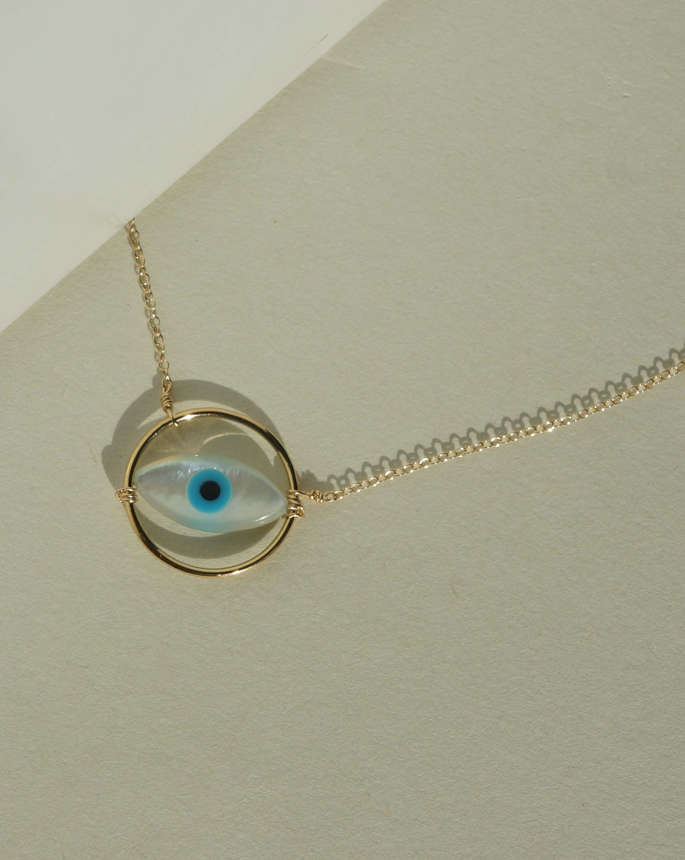 Ino Necklace by KOZAKH. A 16 to 18 inch adjustable length necklace in 14K Gold Filled, featuring a hand carved Mother of Pearl Evil Eye charm inside a ring.