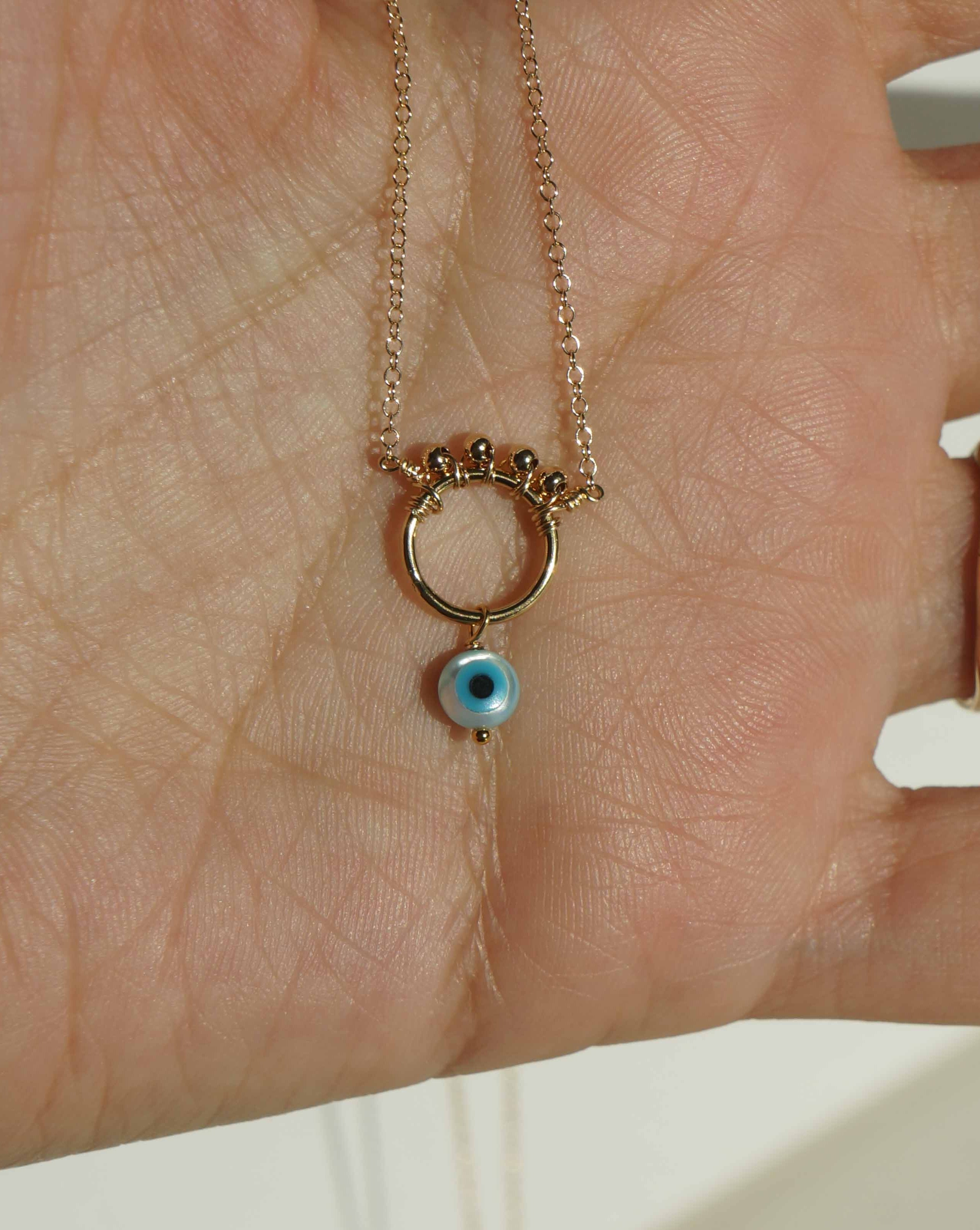 Ivy Necklace by KOZAKH. A 16 to 18 inch adjustable length necklace in 14K Gold Filled, featuring a hand carved Mother of Pearl Evil Eye charm and 2mm Seamless gold beads.