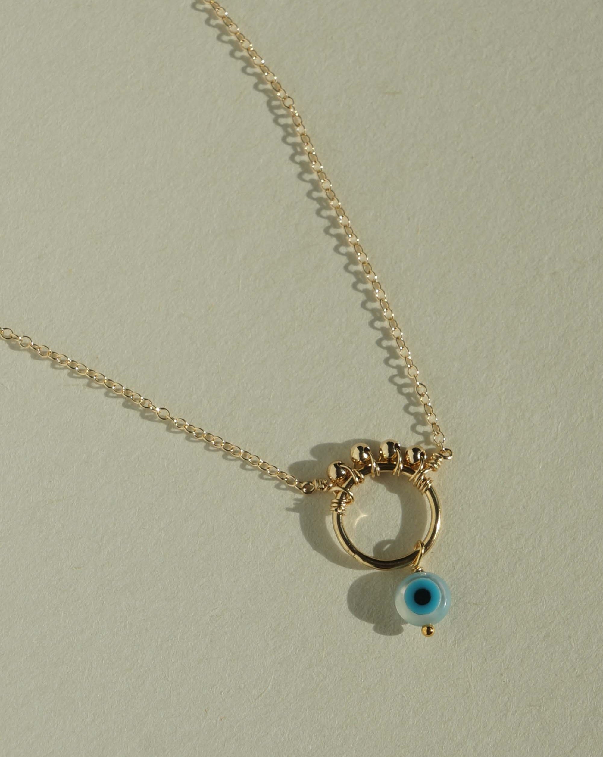 Ivy Necklace by KOZAKH. A 16 to 18 inch adjustable length necklace in 14K Gold Filled, featuring a hand carved Mother of Pearl Evil Eye charm and 2mm Seamless gold beads.