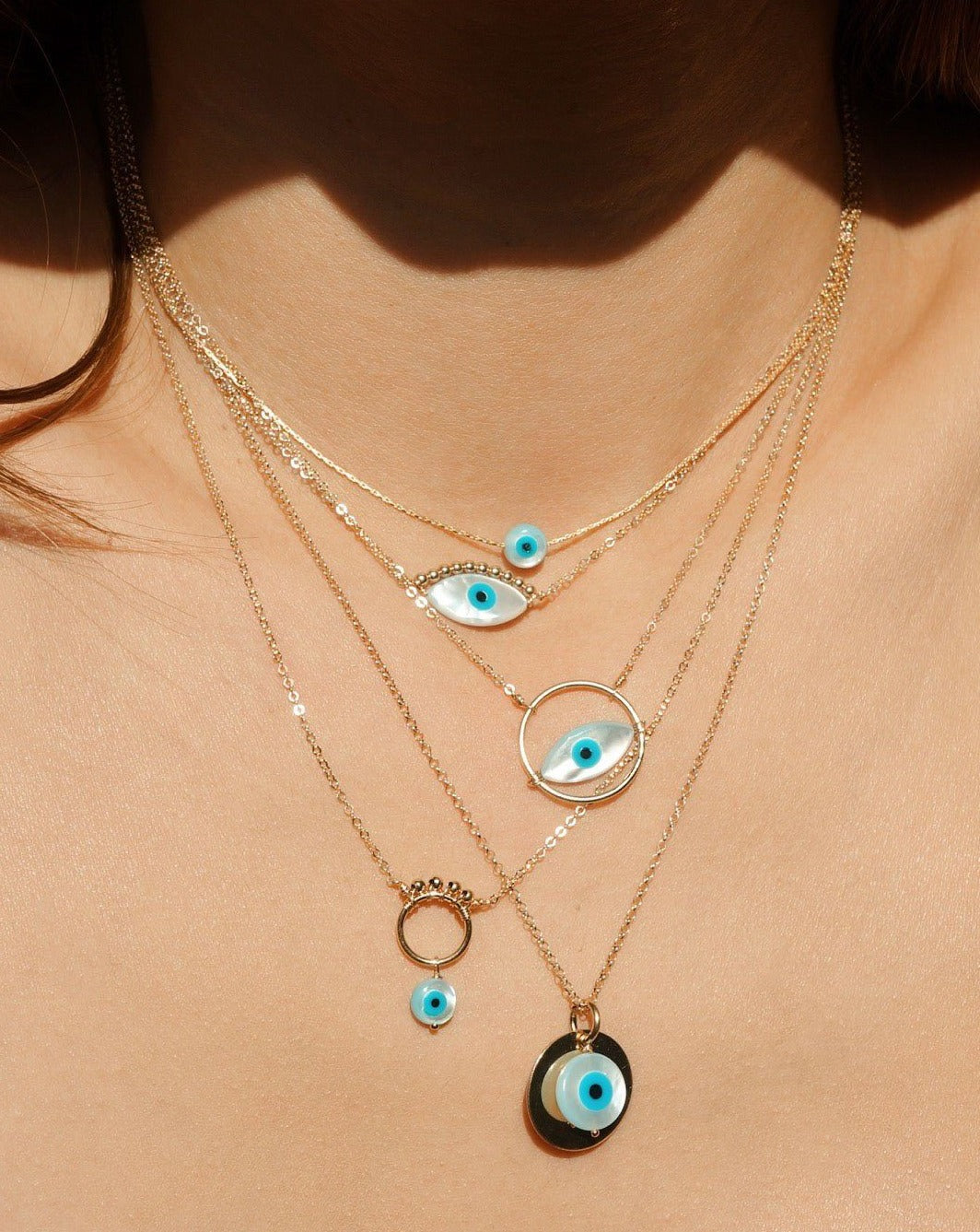 Iza Necklace by KOZAKH. An 18 to 20 inch adjustable length, 1mm thick Rollo chain necklace in 14k Gold Filled, featuring a 16mm Flat Coin and a 7mm hand carved Mother of Pearl evil eye charm.