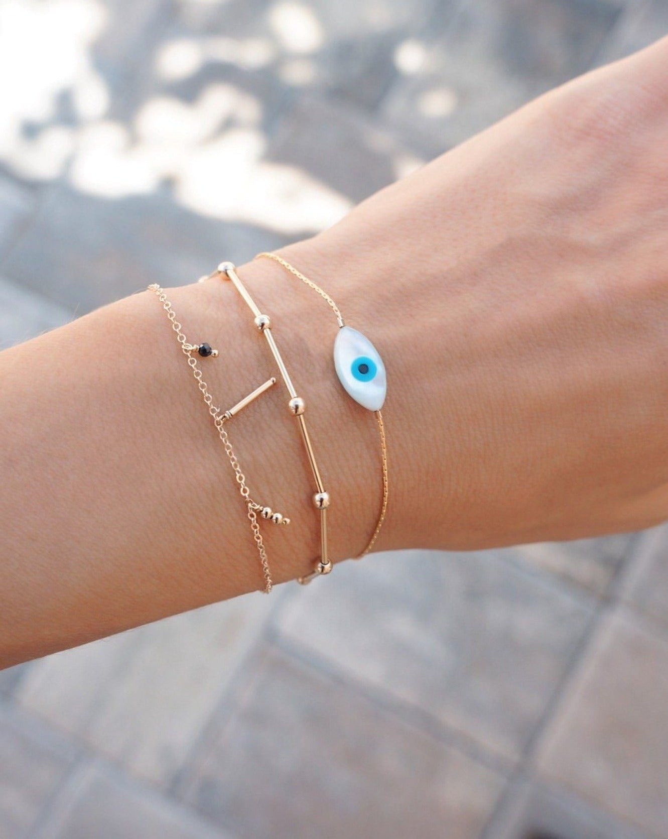 Izu Bracelet by KOZAKH. A 6 to 7 inch adjustable length, 1mm thick cordette chain bracelet in 14K Gold Filled, featuring a hand carved Mother of Pearl evil eye charm.