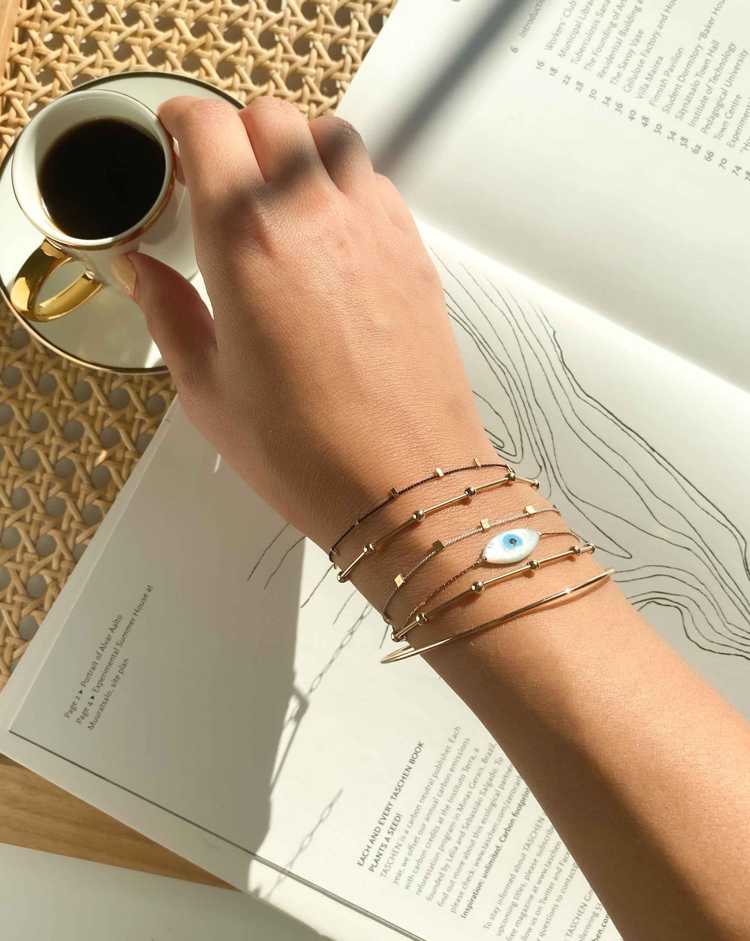 Izu Bracelet by KOZAKH. A 6 to 7 inch adjustable length, 1mm thick cordette chain bracelet in 14K Gold Filled, featuring a hand carved Mother of Pearl evil eye charm.