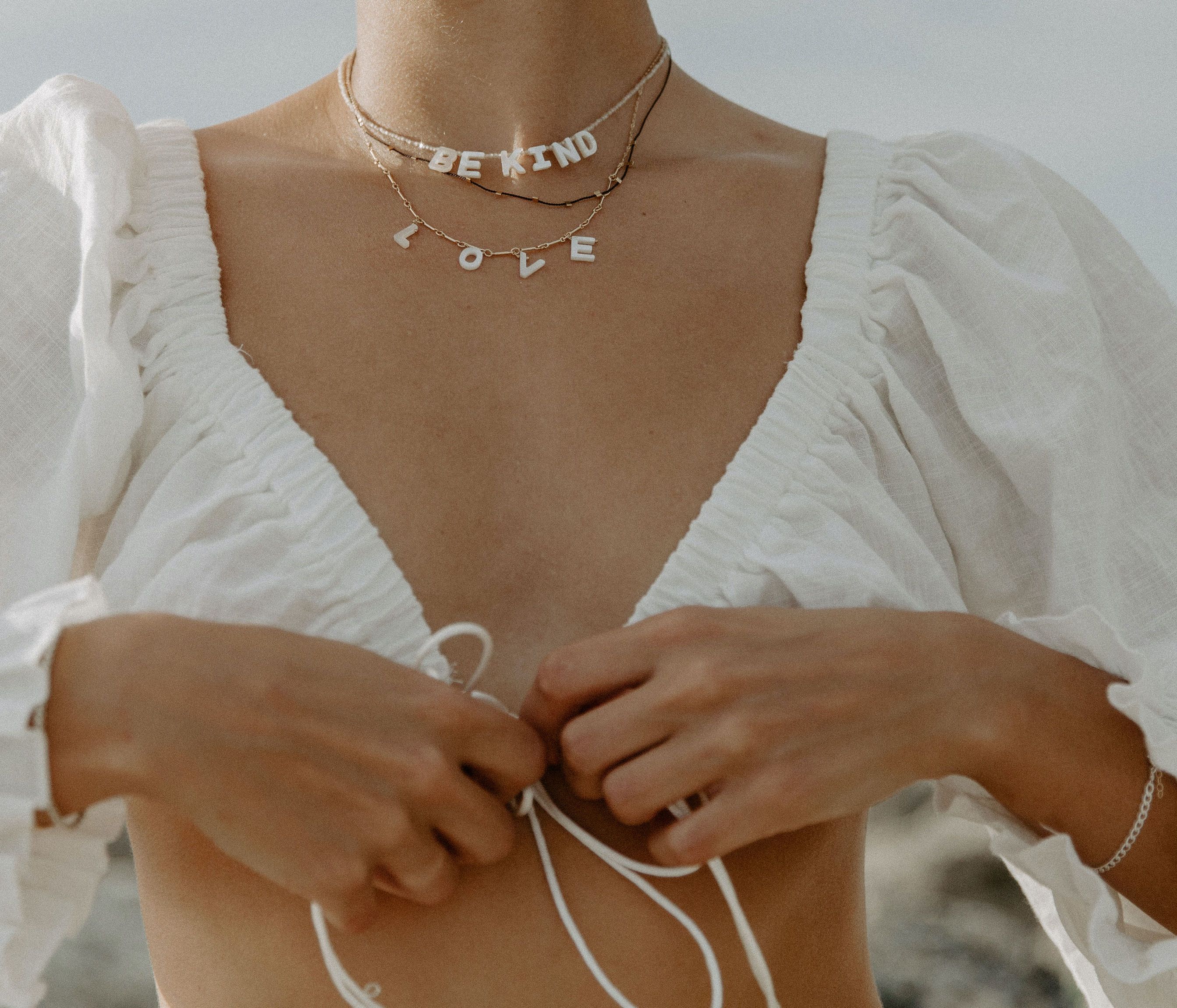 Love Necklace by KOZAKH. A 16 to 18 inch adjustable length necklace with linked bar chain on bottom half and flat link chain on top half, crafted in 14K Gold Filled, featuring a customizable word made from hand carved Mother of Pearl letters.