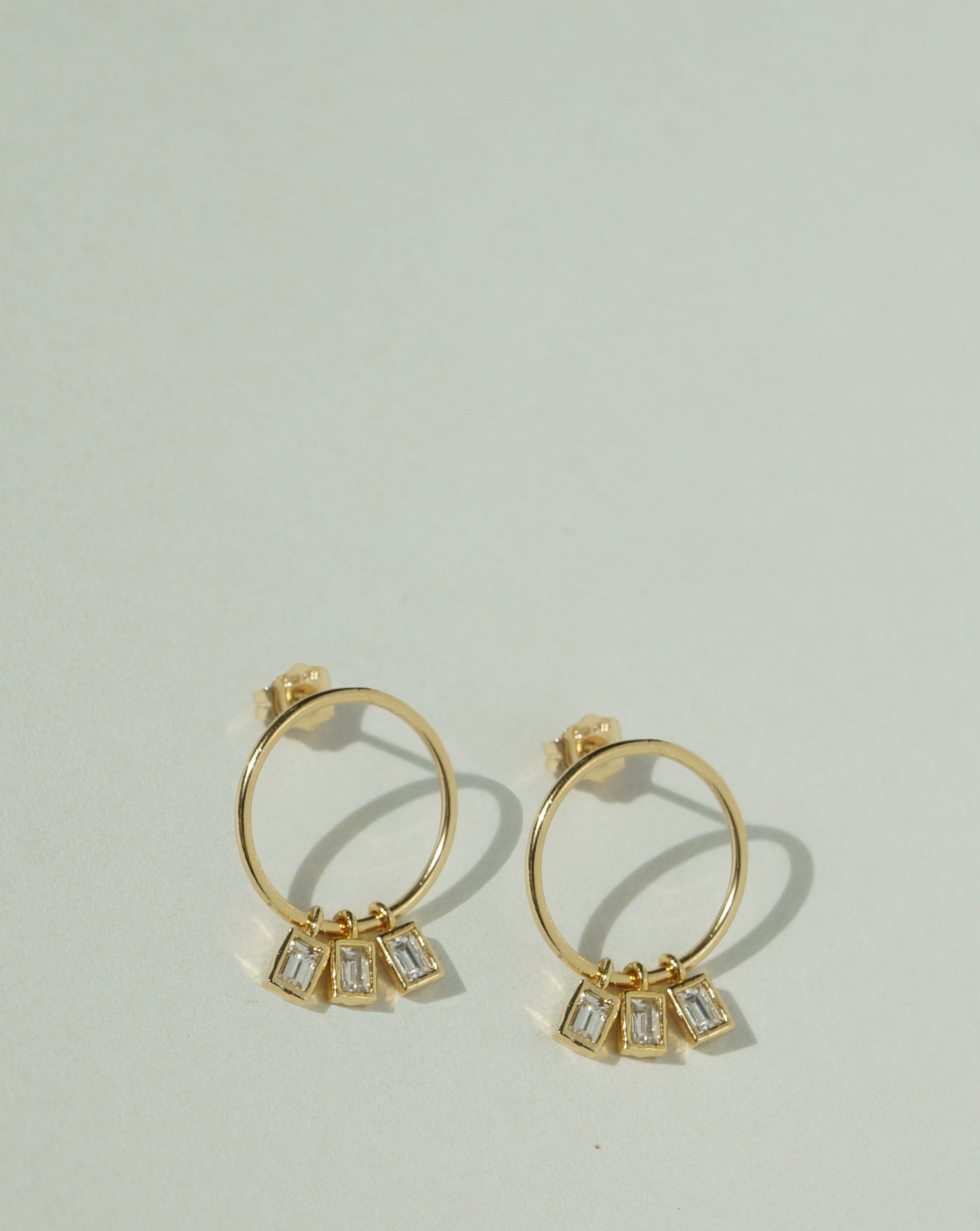 Madison Earrings by KOZAKH. Short dangling style stud earrings crafted in 14K Gold Filled, featuring a hoop and square cut Cubic Zirconia gems.