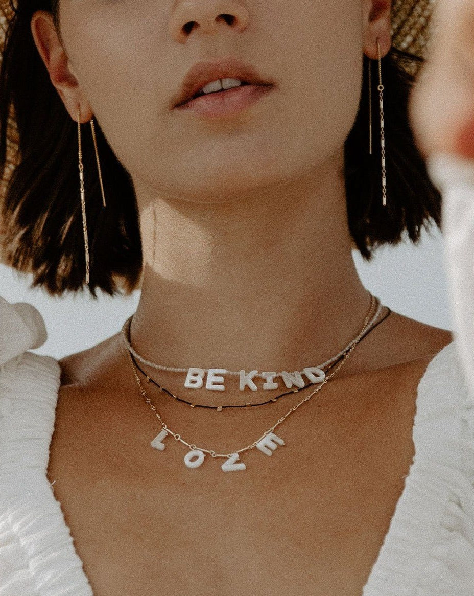 Mama Necklace by KOZAKH. A 16 to 18 inch adjustable length necklace with linked bar chain on bottom half and flat link chain on top half, crafted in 14K Gold Filled, featuring a customizable word made from hand carved Mother of Pearl letters.
