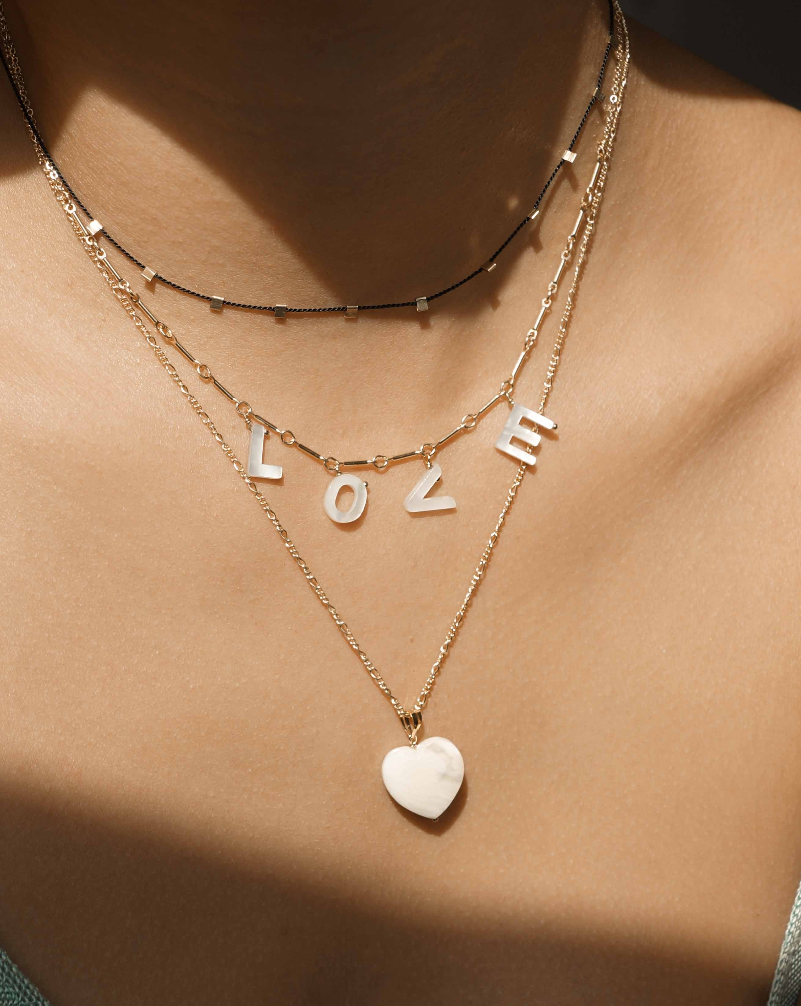 Mama Necklace by KOZAKH. A 16 to 18 inch adjustable length necklace with linked bar chain on bottom half and flat link chain on top half, crafted in 14K Gold Filled, featuring a customizable word made from hand carved Mother of Pearl letters.