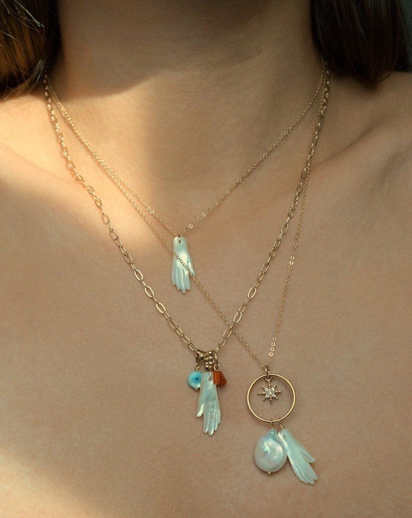 Manola Necklace by KOZAKH. An 18 to 20 inch adjustable length necklace in 14k Gold Filled, featuring a hand carved Mother of Pearl hand, a hand carved Mother of Pearl evil eye and a red coral bead.