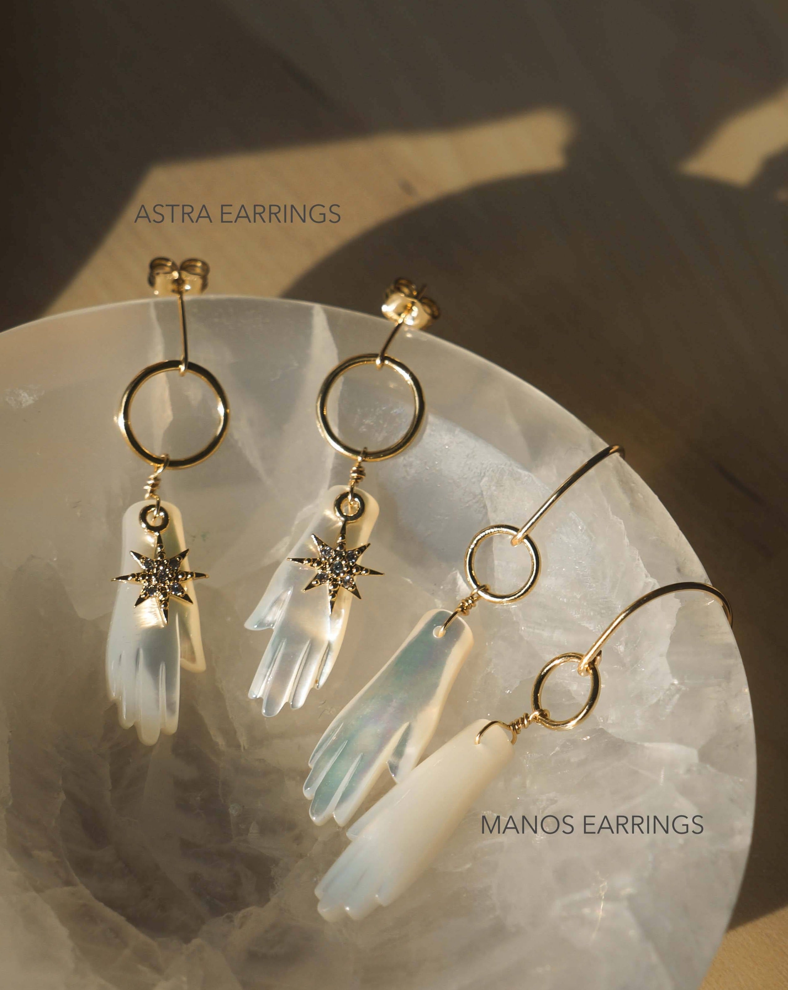 Manos Hoop Earrings by KOZAKH. Hook earrings crafted in 14K Gold Filled, featuring a hand carved Mother of Pearl hand.
