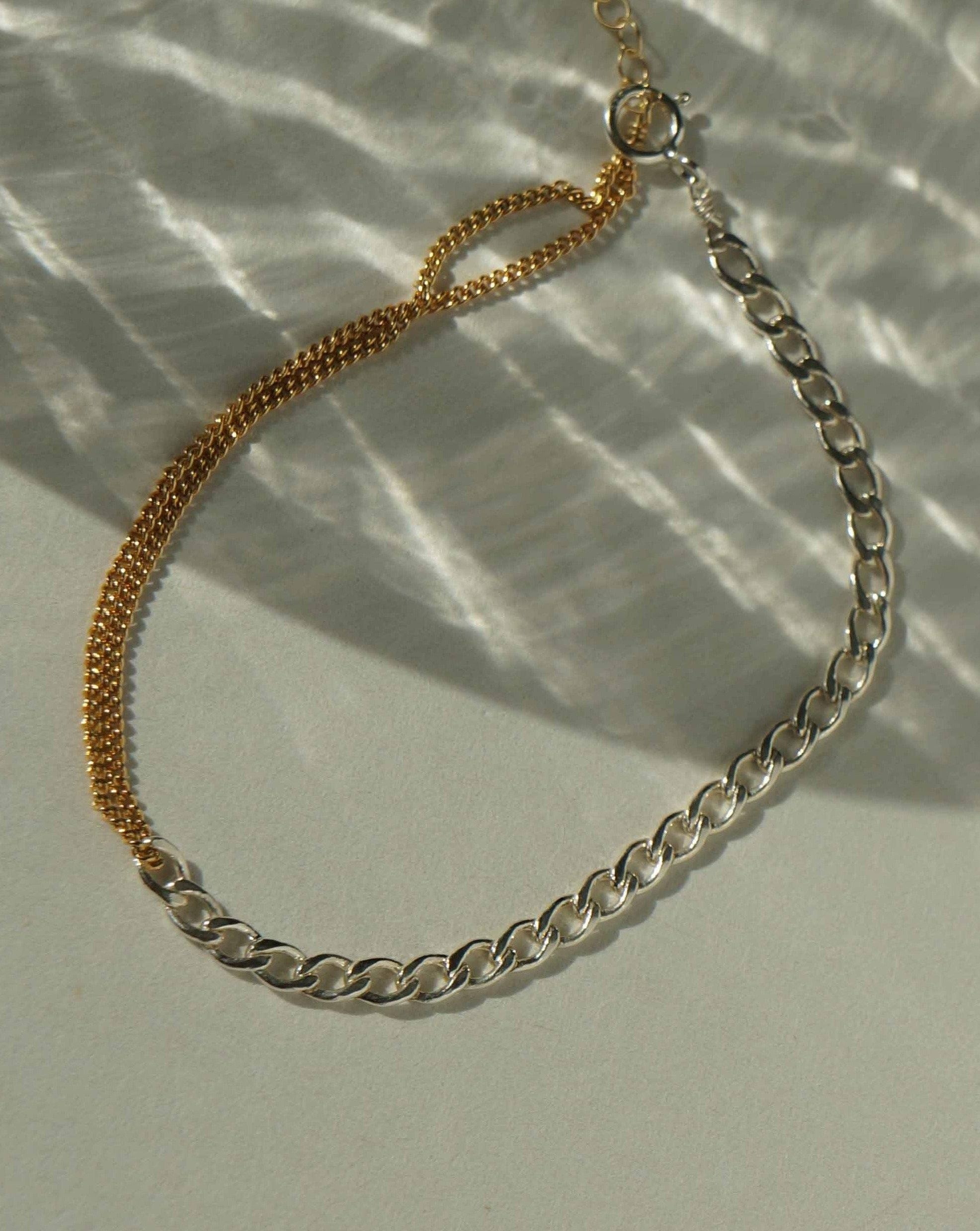 Moni Bracelet by KOZAKH. A 6 to 7 inch adjustable length two tone bracelet with 1mm Gold Filled flat curb chain on one half and 3mm Sterling Silver Cuban link chain on the other half.