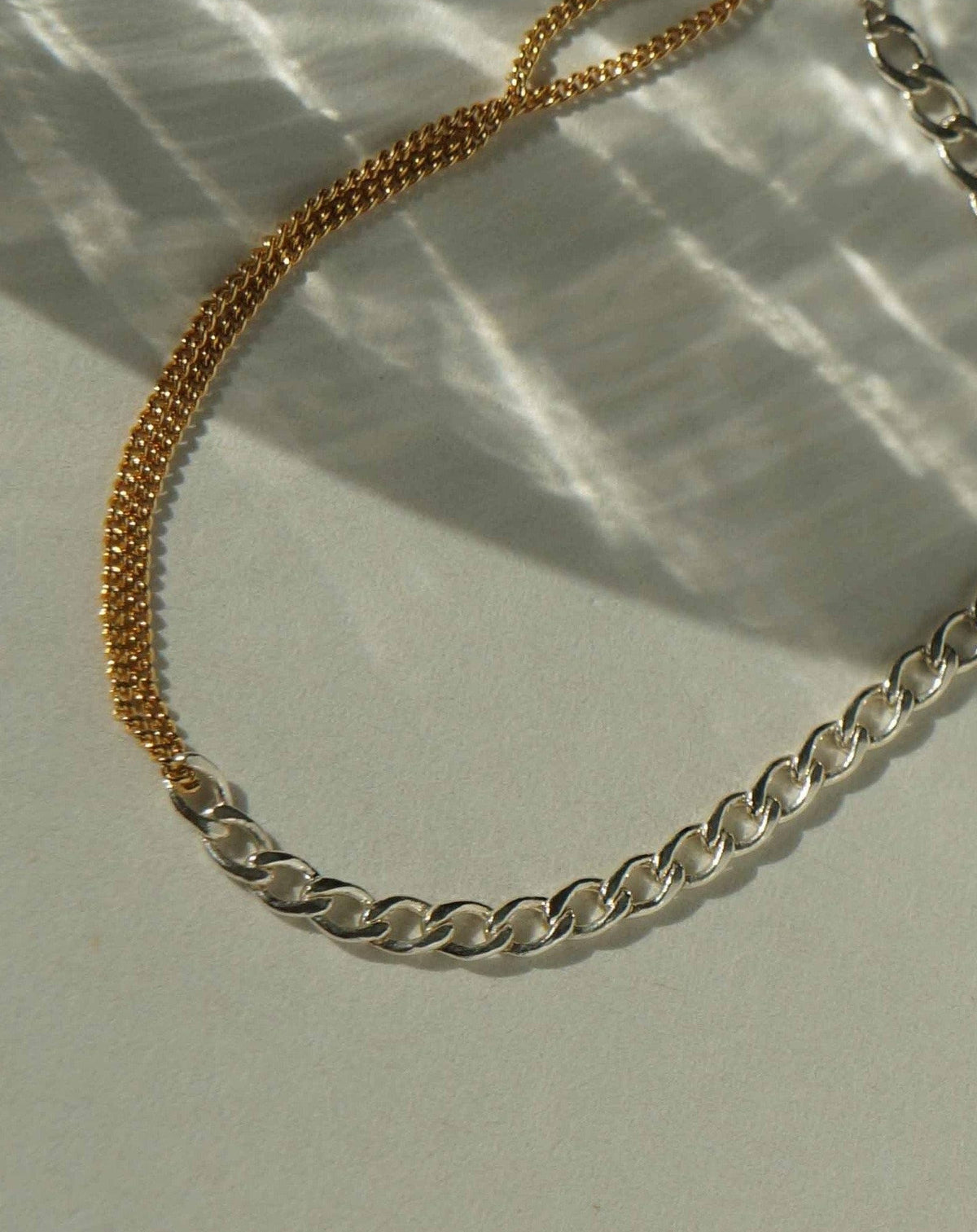 Moni Bracelet by KOZAKH. A 6 to 7 inch adjustable length two tone bracelet with 1mm Gold Filled flat curb chain on one half and 3mm Sterling Silver Cuban link chain on the other half.