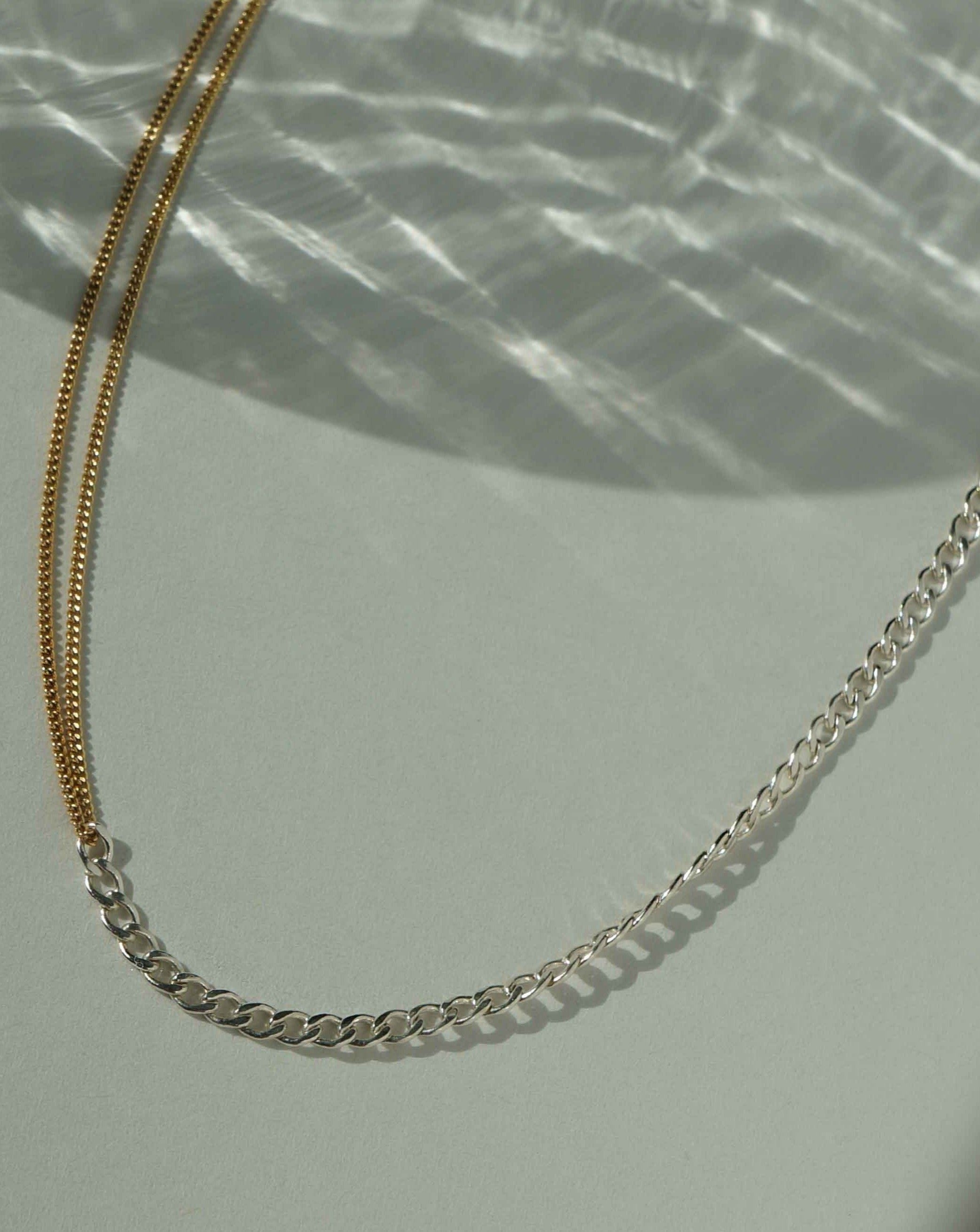 Monica Necklace by KOZAKH. A 14 to 16 inch adjustable length two tone necklace with gold box chain on one half and silver braided chain on the other half.