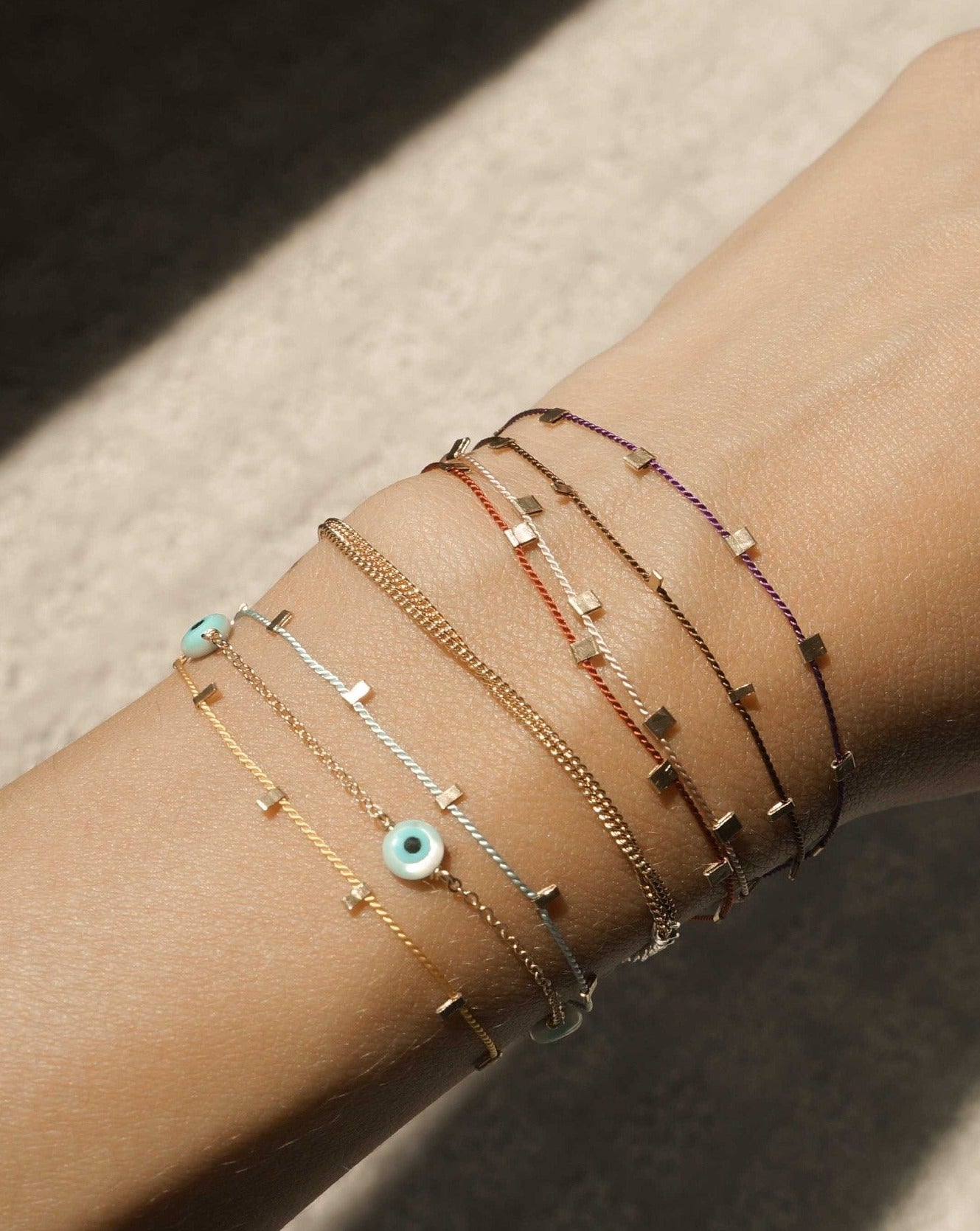 Ojitos Bracelet by KOZAKH. A 6 to 7 inch adjustable length bracelet, crafted in 14K Gold Filled, featuring hand carved Mother of Pearl Evil Eye charms. 