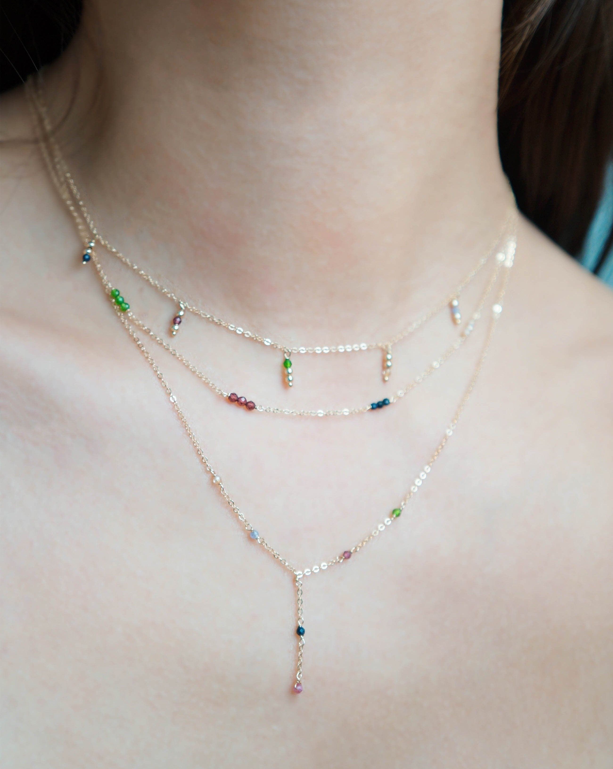 Safron Necklace by KOZAKH. A 16 to 18 inch adjustable length, lariat style necklace, crafted in 14K Gold Filled, featuring 2mm Faceted round Emerald, Garnet, Sapphire, Tourmaline, Tanzanite and Topaz.
