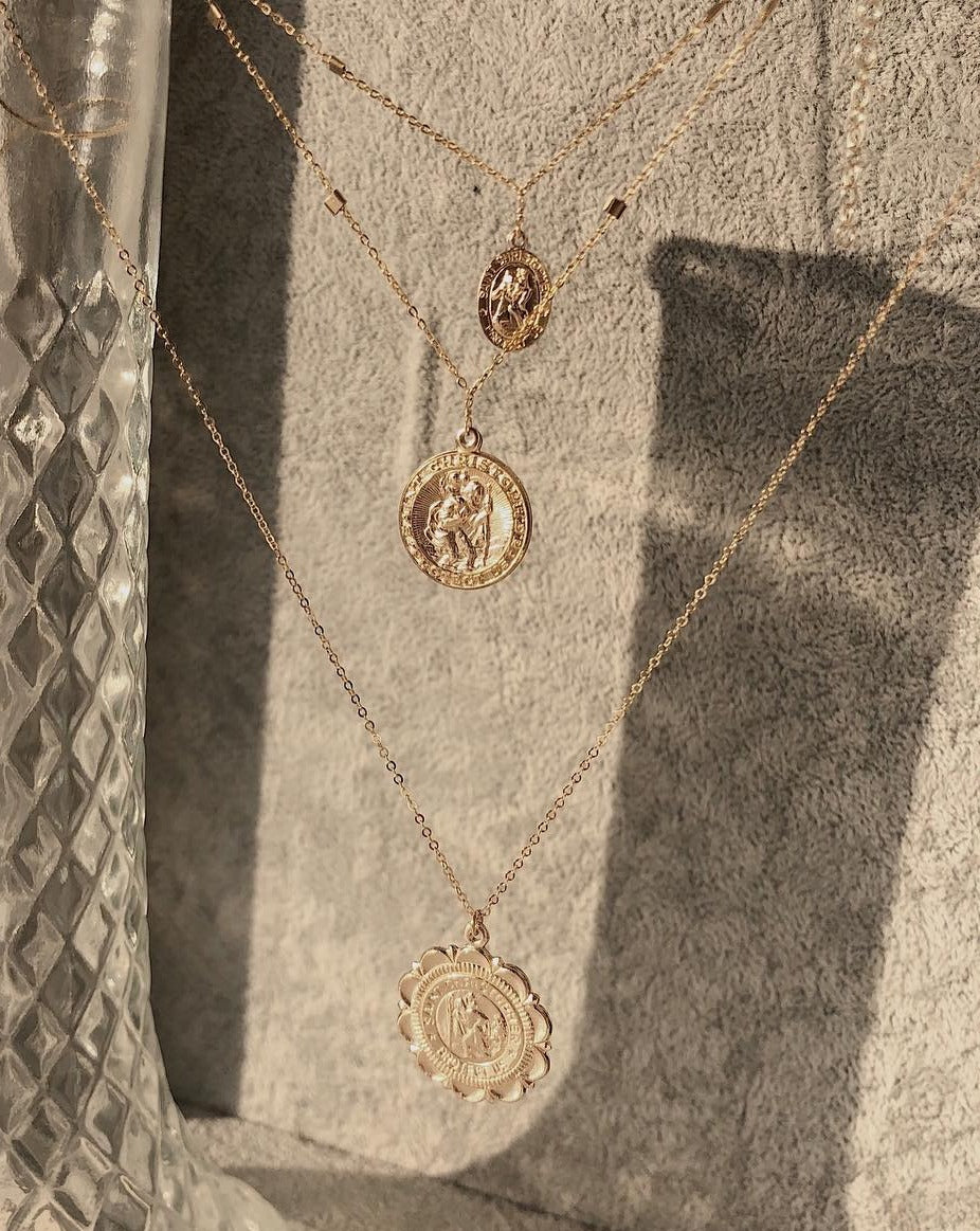 San Cris Necklace by KOZAKH. A 16 to 18 inch adjustable length necklace, crafted in 14K Gold Filled, featuring a 16mm Saint Christopher Medallion.