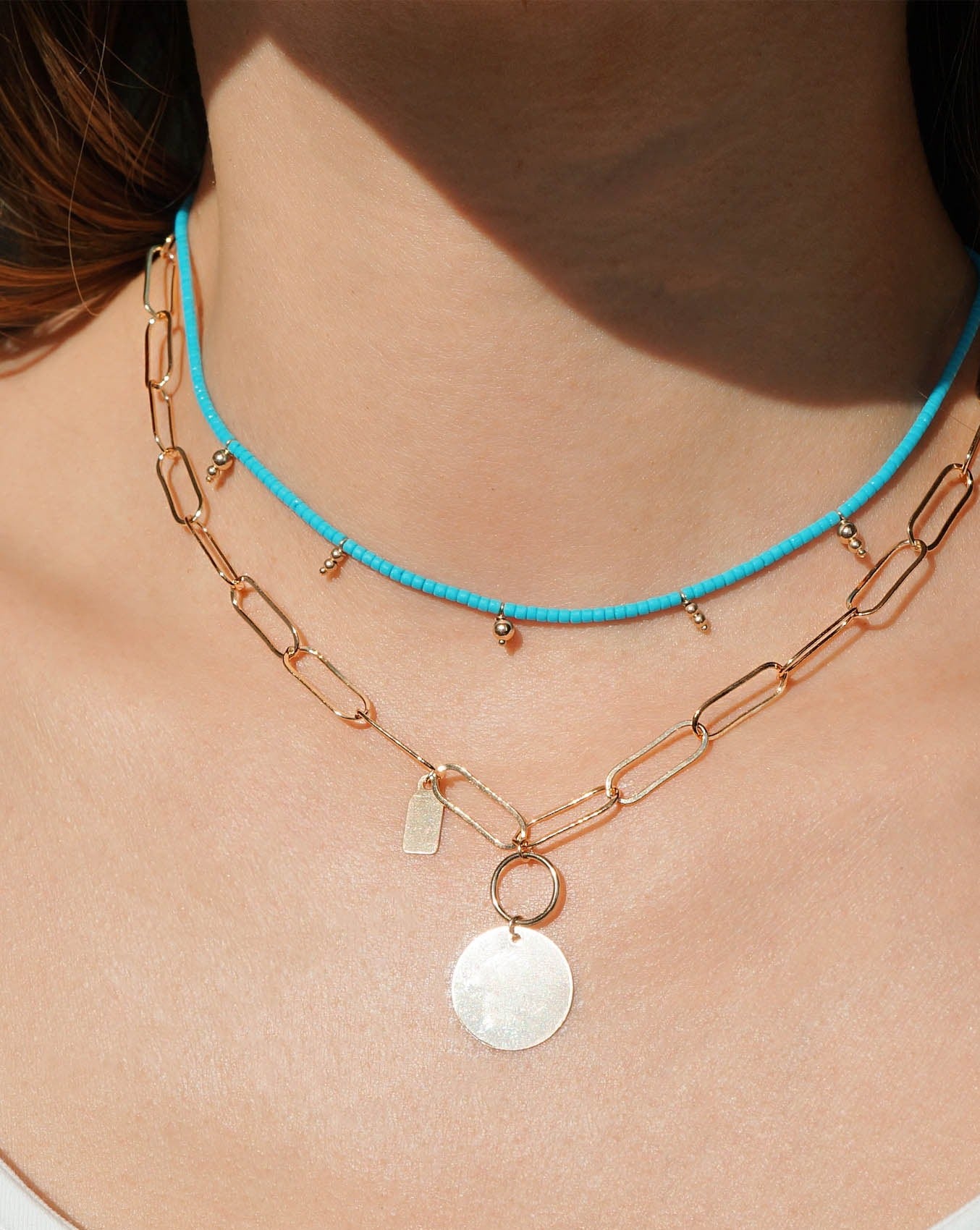 Scarlett Necklace by KOZAKH. A 16 to 18 inch adjustable length, flat oval chain necklace, crafted in 14K Gold Filled, featuring a 3x5mm Tag and a 16mm Flat coin.