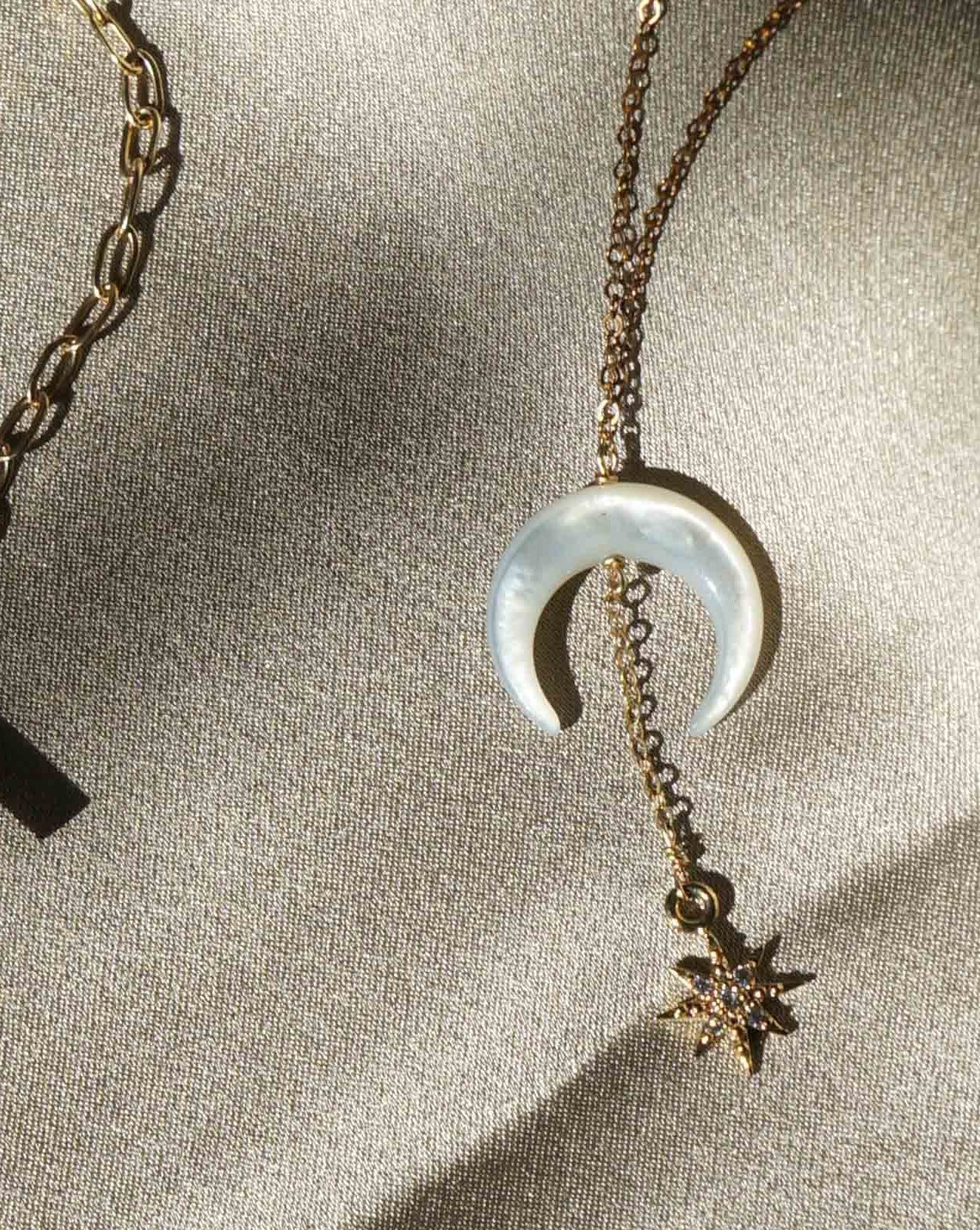 Stella Necklace by KOZAKH. A 16 to 18 inch adjustable length necklace, crafted in 14K Gold Filled, featuring a hand carved Mother of Pearl crescent moon charm and a Cubic Zirconia encrusted 6 point star.
