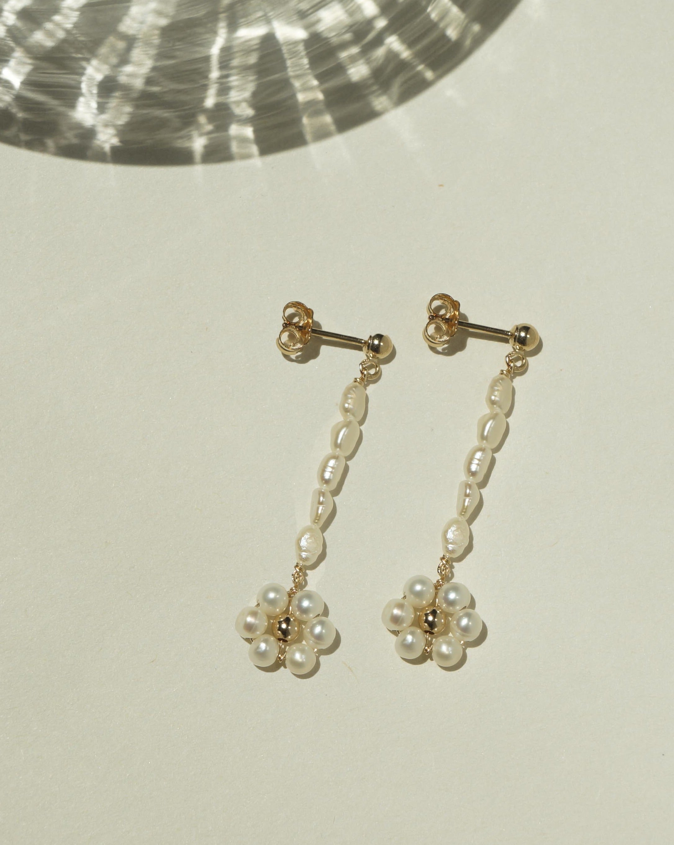 Sunflower Earrings by KOZAKH. 3mm Ball stud drop earrings with 2 inches drop length, crafted in 14K Gold Filled, featuring 3mm rice freshwater Pearls and 3-4mm round freshwater Pearls forming a flower charm.