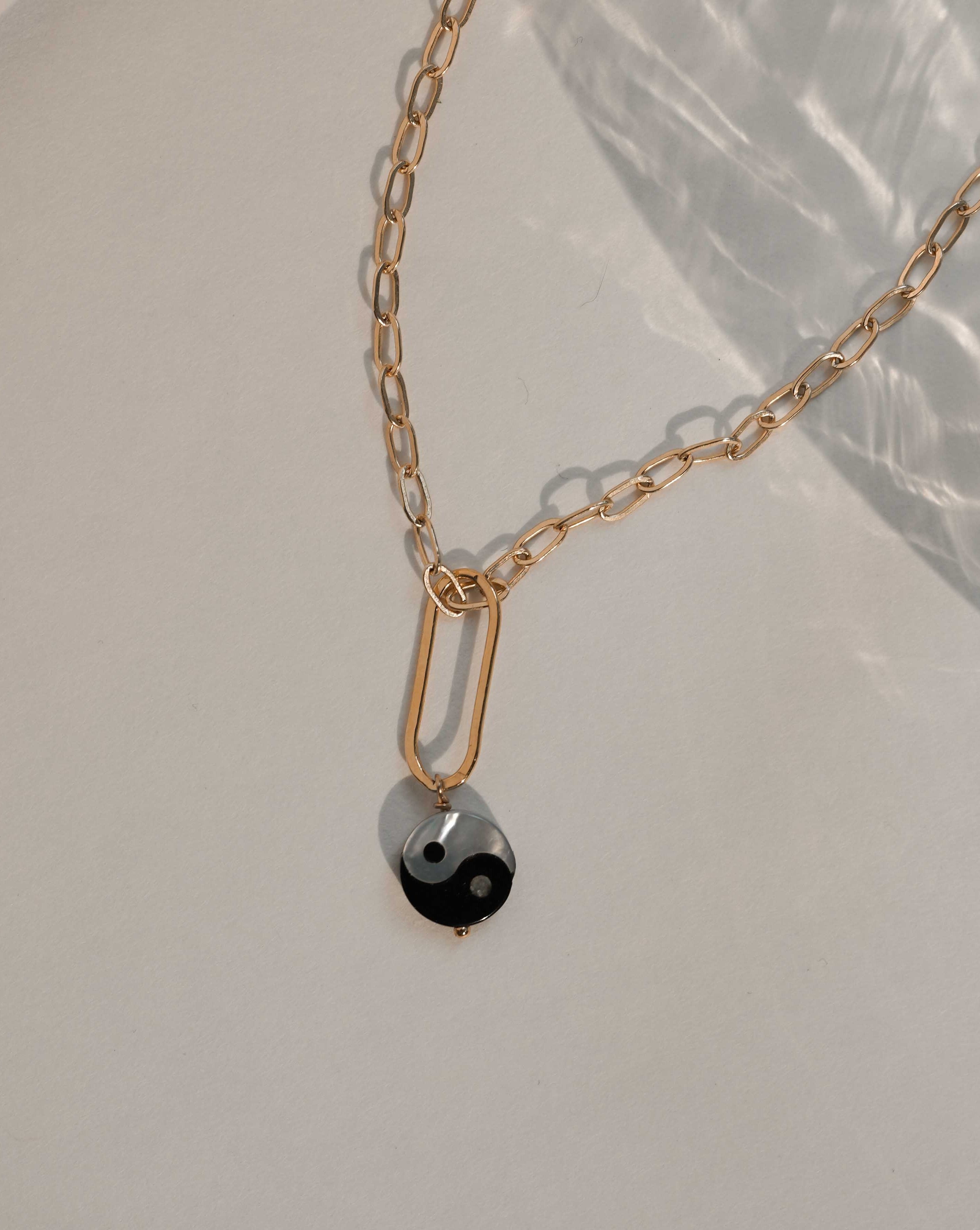 Yin Yang Necklace by KOZAKH. A 16 to 18 inch adjustable length, flat link cable chain necklace, crafted in 14K Gold Filled, featuring a hand carved Mother of pearl Yin Yang charm.