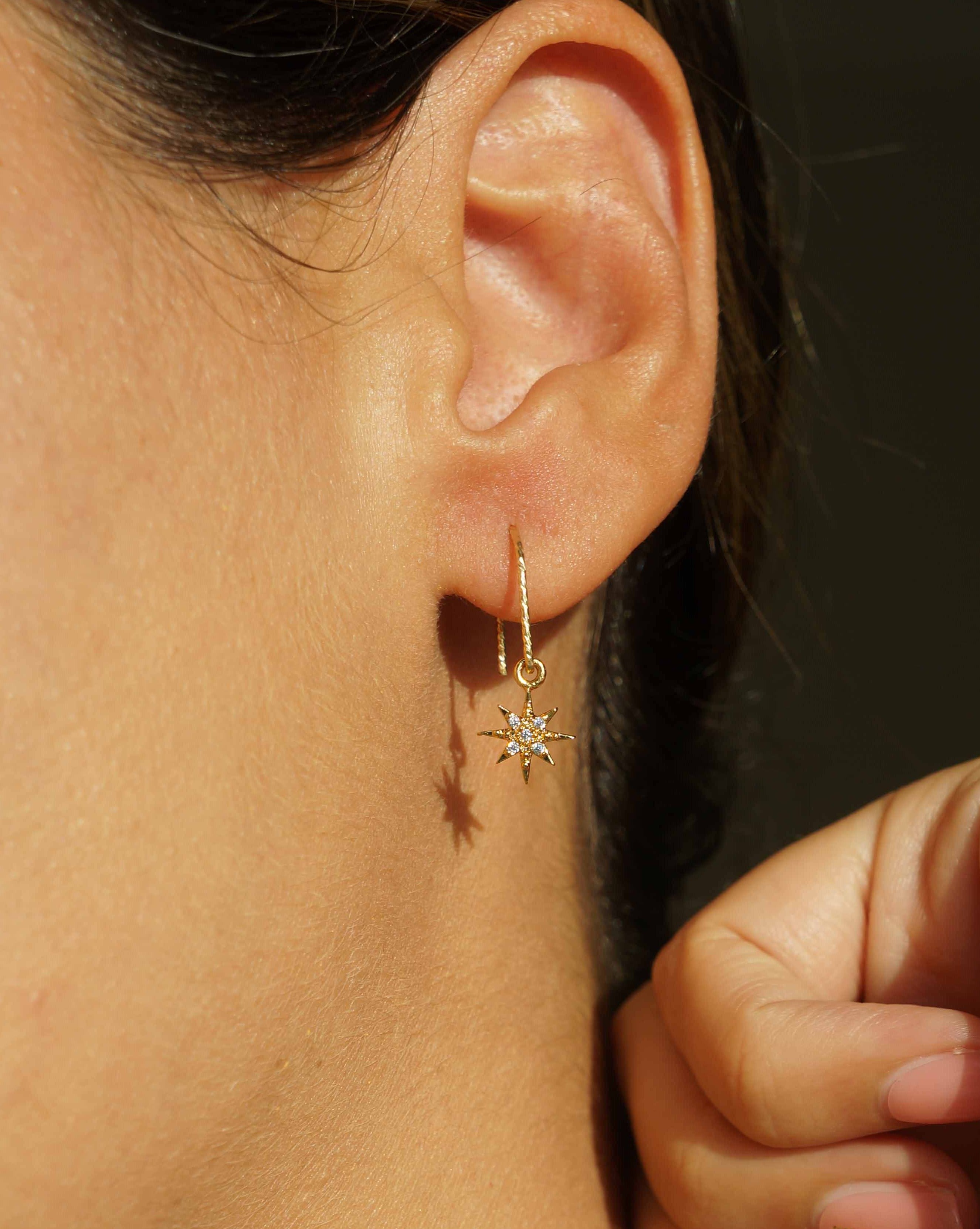 You Star Earrings by KOZAKH. Diamond textured hook earrings, crafted in 14K Gold Filled, featuring a Cubic Zirconia encrusted 8 point star charm.