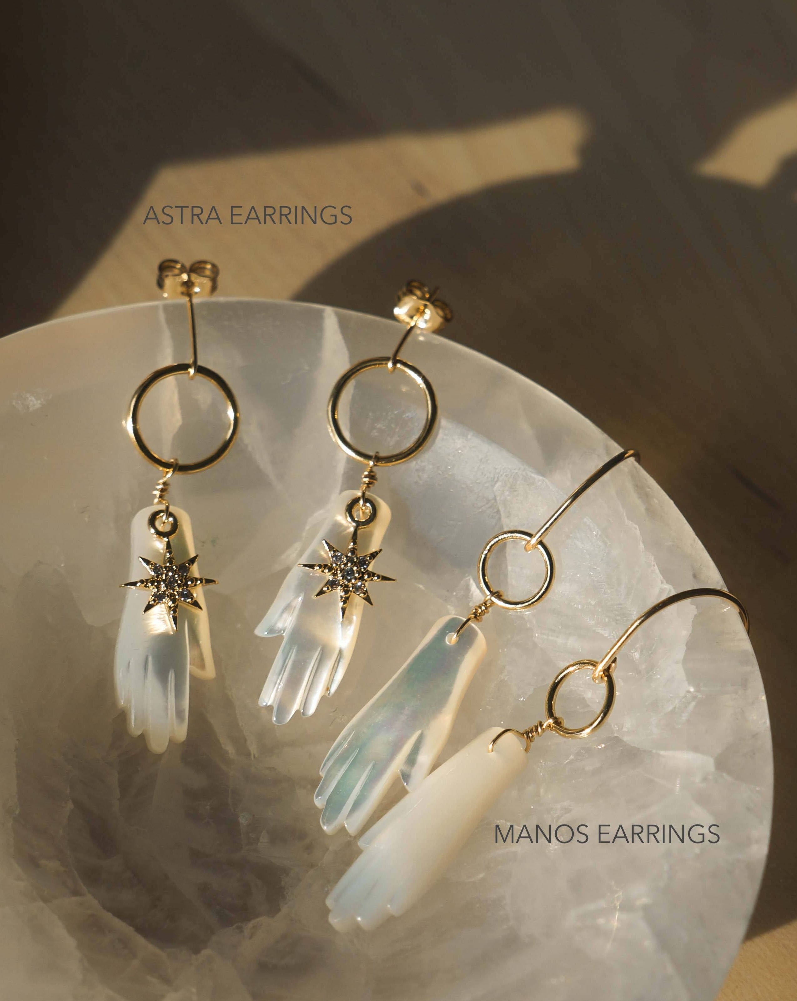 Astra Earrings by KOZAKH. Dangling earrings in 14K Gold Filled, featuring a hand carved Mother of Pearl hand charm and a Cubic Zirconia star charm.