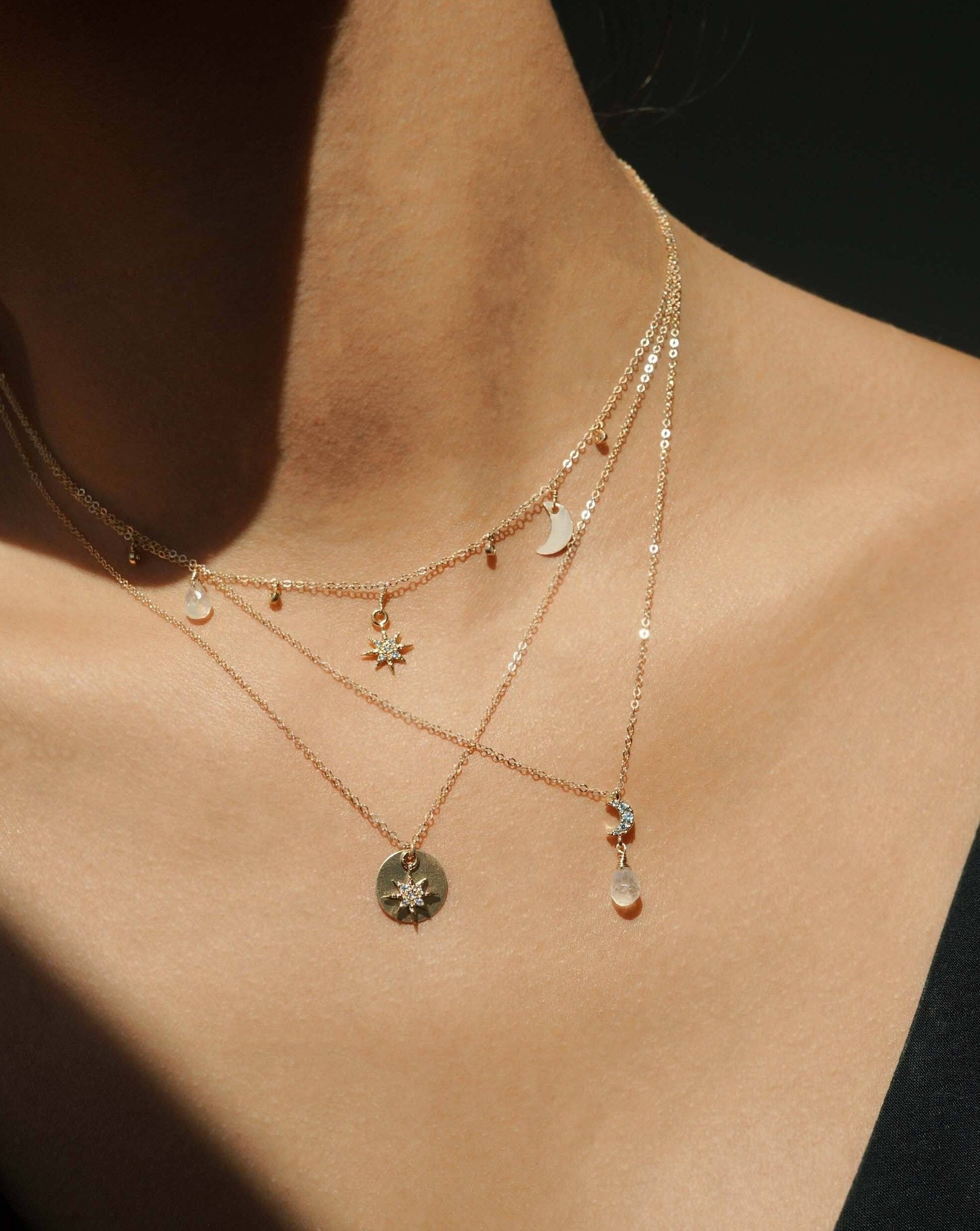 Caelum Necklace by KOZAKH. A 16 to 18 inch adjustable length necklace in 14K Gold Filled, featuring a faceted Moonstone droplet and a Cubic Zirconia encrusted moon charm.