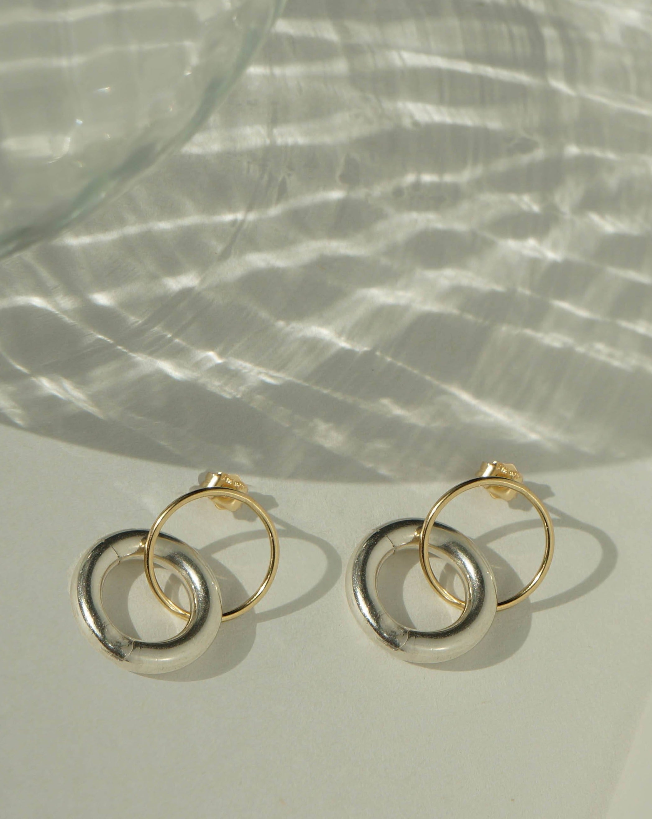Charlotte Earrings by KOZAKH. Stud earrings in 14K Gold Filled, featuring a dangling and removable silver huggies.