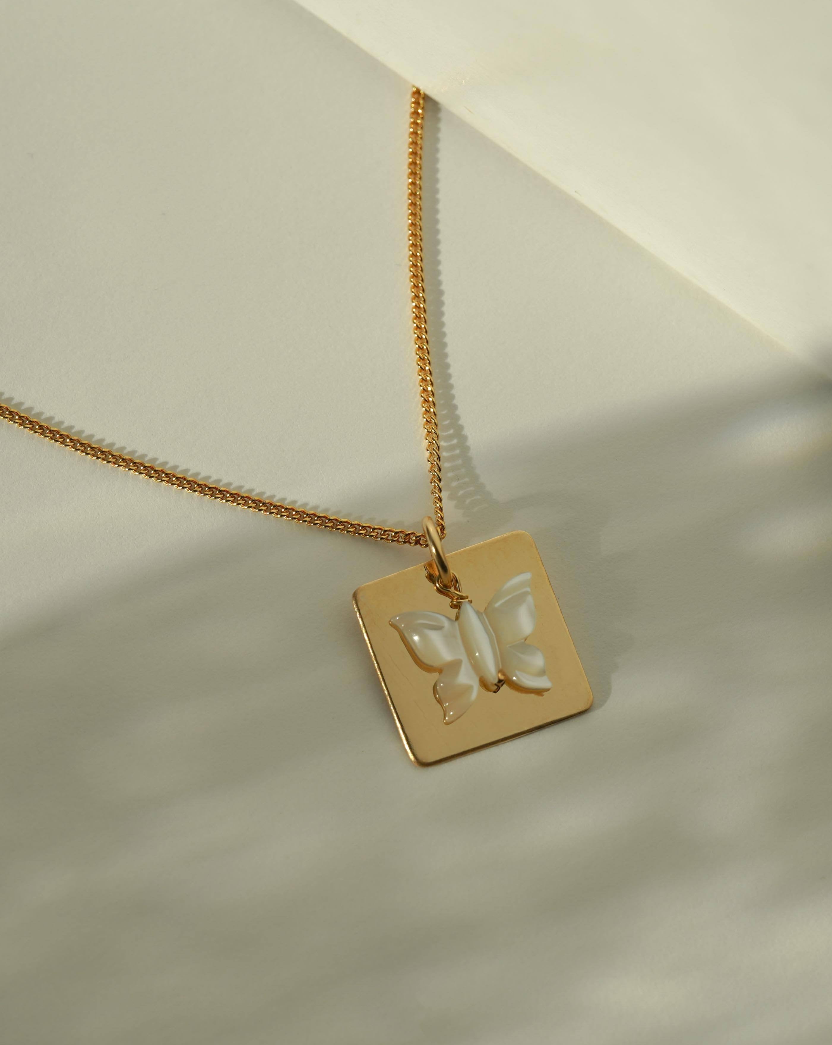 Esperanza Necklace by KOZAKH. An 18 to 20 inch adjustable length necklace in 14K Gold Filled, featuring a Mother of pearl butterfly charm and a 16mm Square pendant.