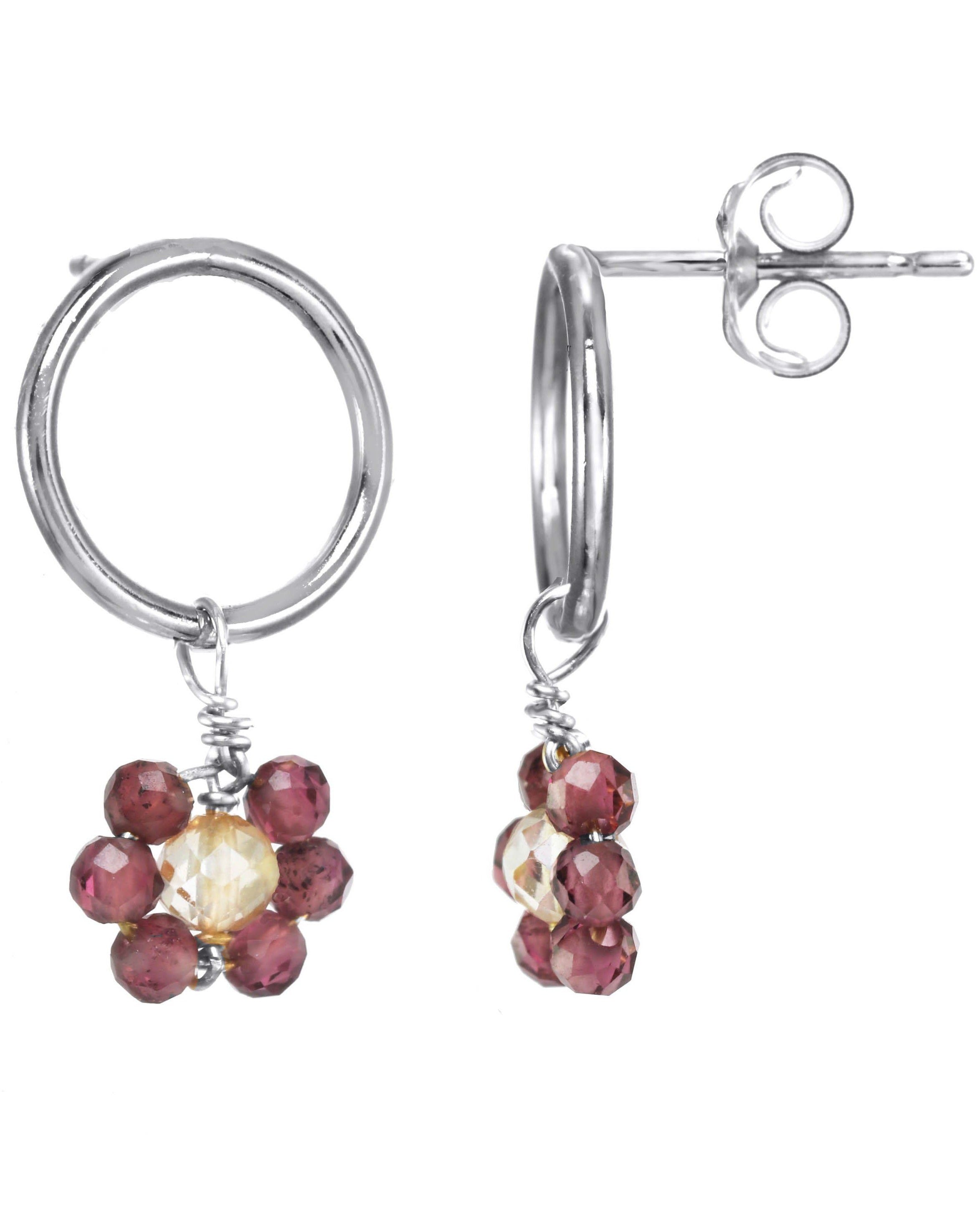 Florcitas Earrings by KOZAKH. 10mm circle studs, crafted in Sterling Silver, featuring 2mm Garnet gems and 3mm Imperial Topaz forming a daisy.