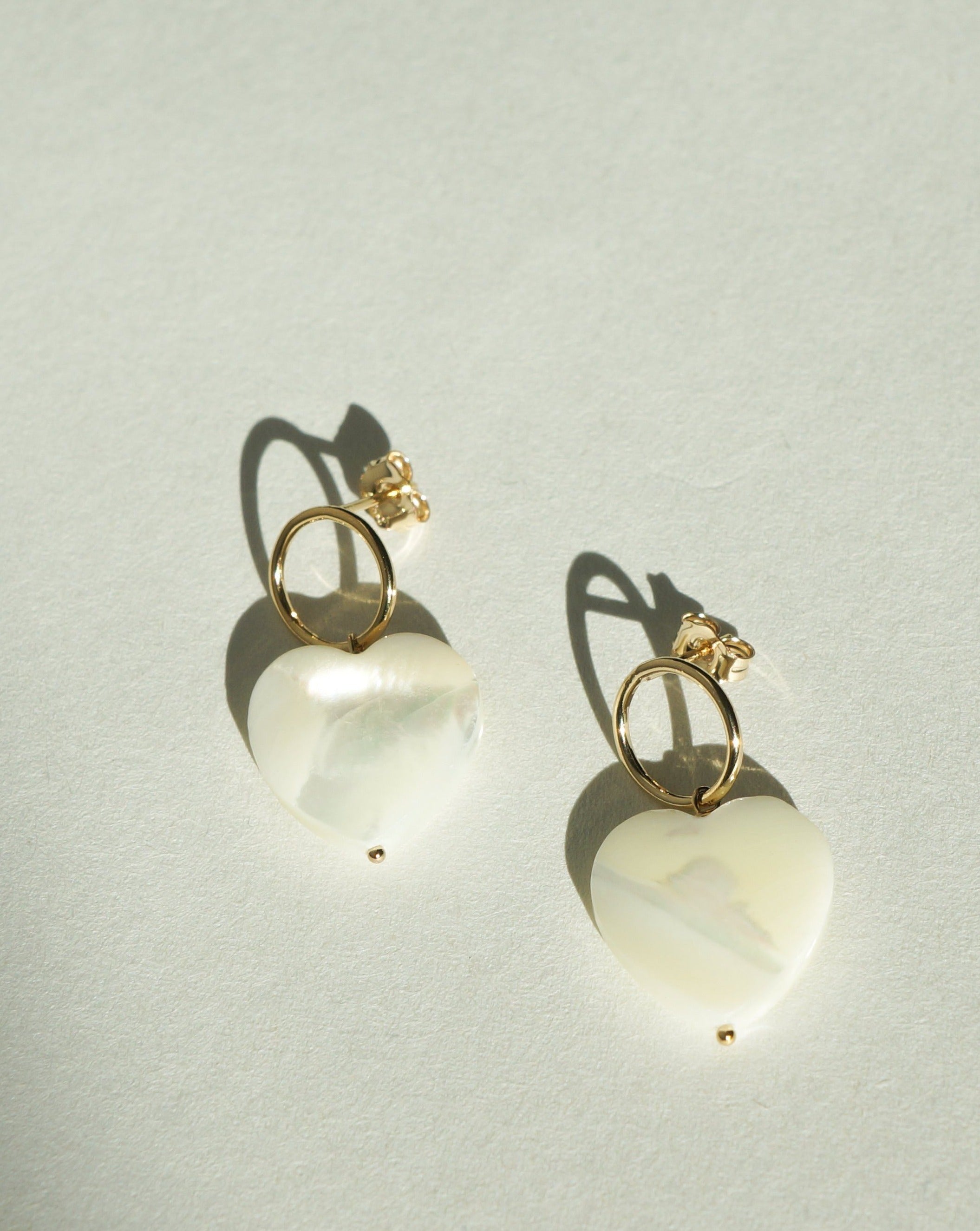 Heart Earrings by KOZAKH. Stud earrings, crafted in 14K Gold Filled, with hoop and hand carved faceted Mother of Pearl heart charm.