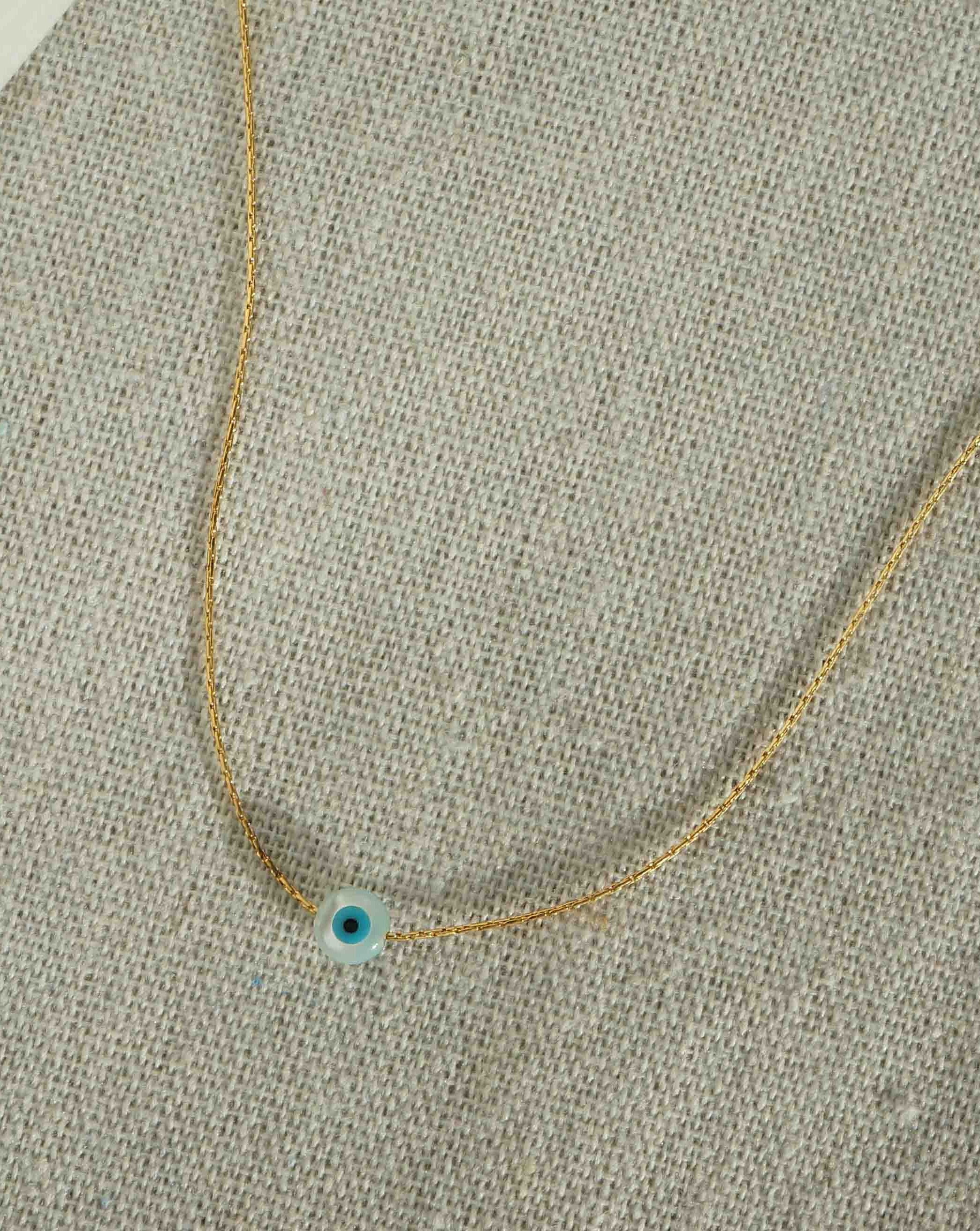 Idra Necklace by KOZAKH. A 16 to 18 inch adjustable length, 1mm thick cordette chain necklace in 14K Gold Filled, featuring a 5mm hand carved Mother of Pearl Evil Eye charm.
