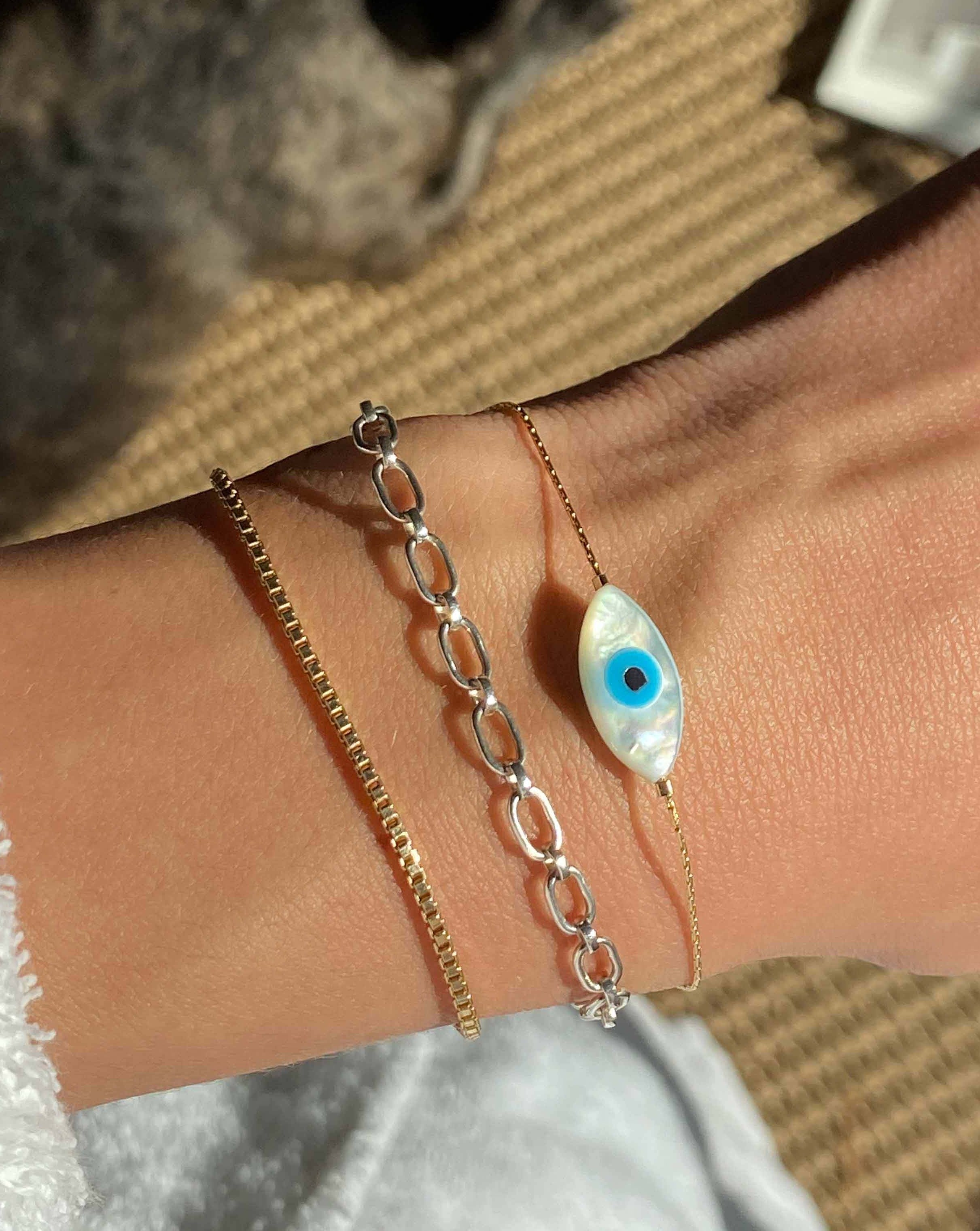Izu Bracelet by KOZAKH. A 6 to 7 inch adjustable length, 1mm thick cordette chain bracelet in 14K Gold Filled, featuring a hand carved Mother of Pearl evil eye charm.