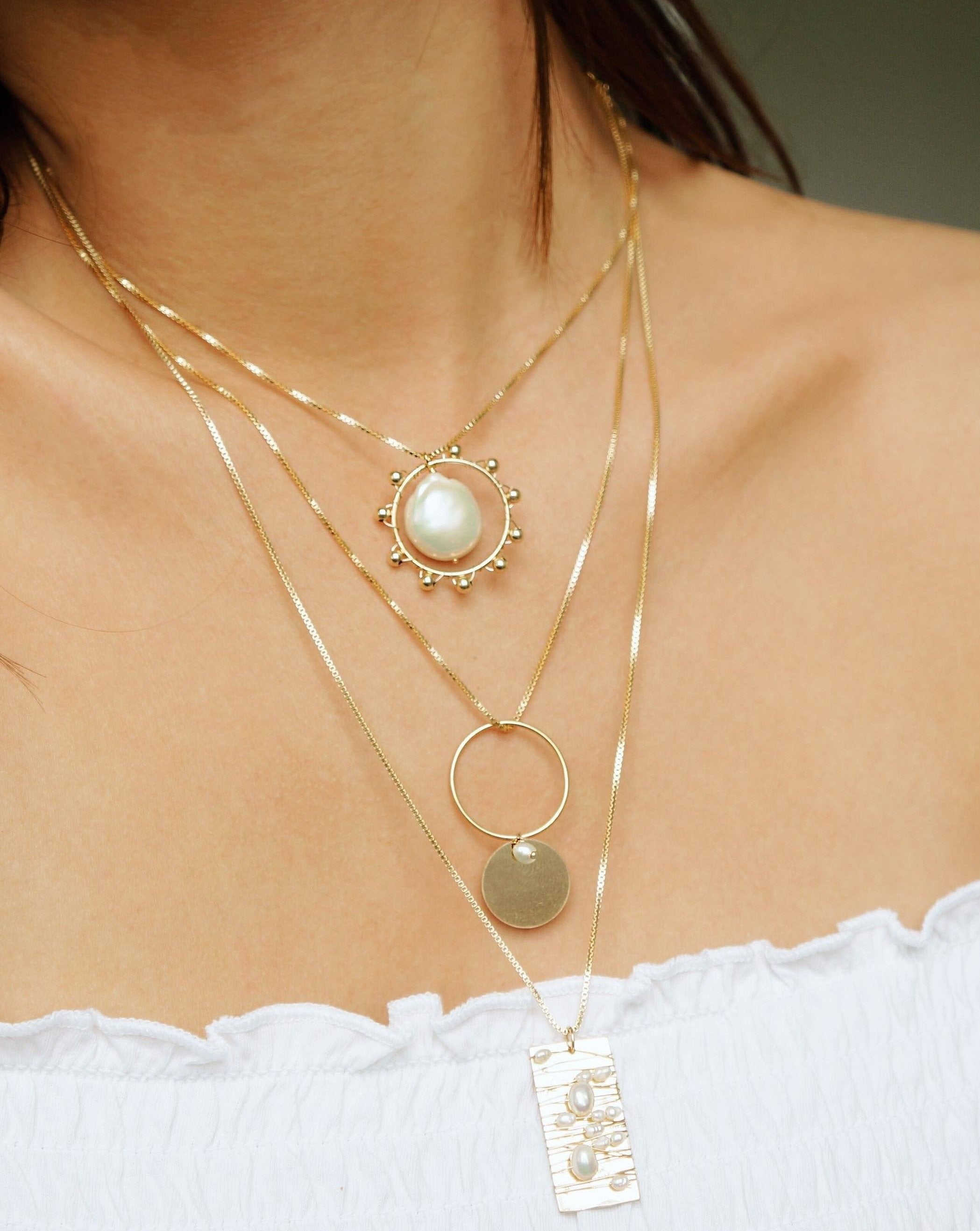 Kuru Necklace by KOZAKH. A 16 to 18 inch adjustable length, 1mm box chain necklace, crafted in 14K Gold Filled, featuring a 20mm x 15mm Baroque Pearl inside a ring embellished with gold beads.