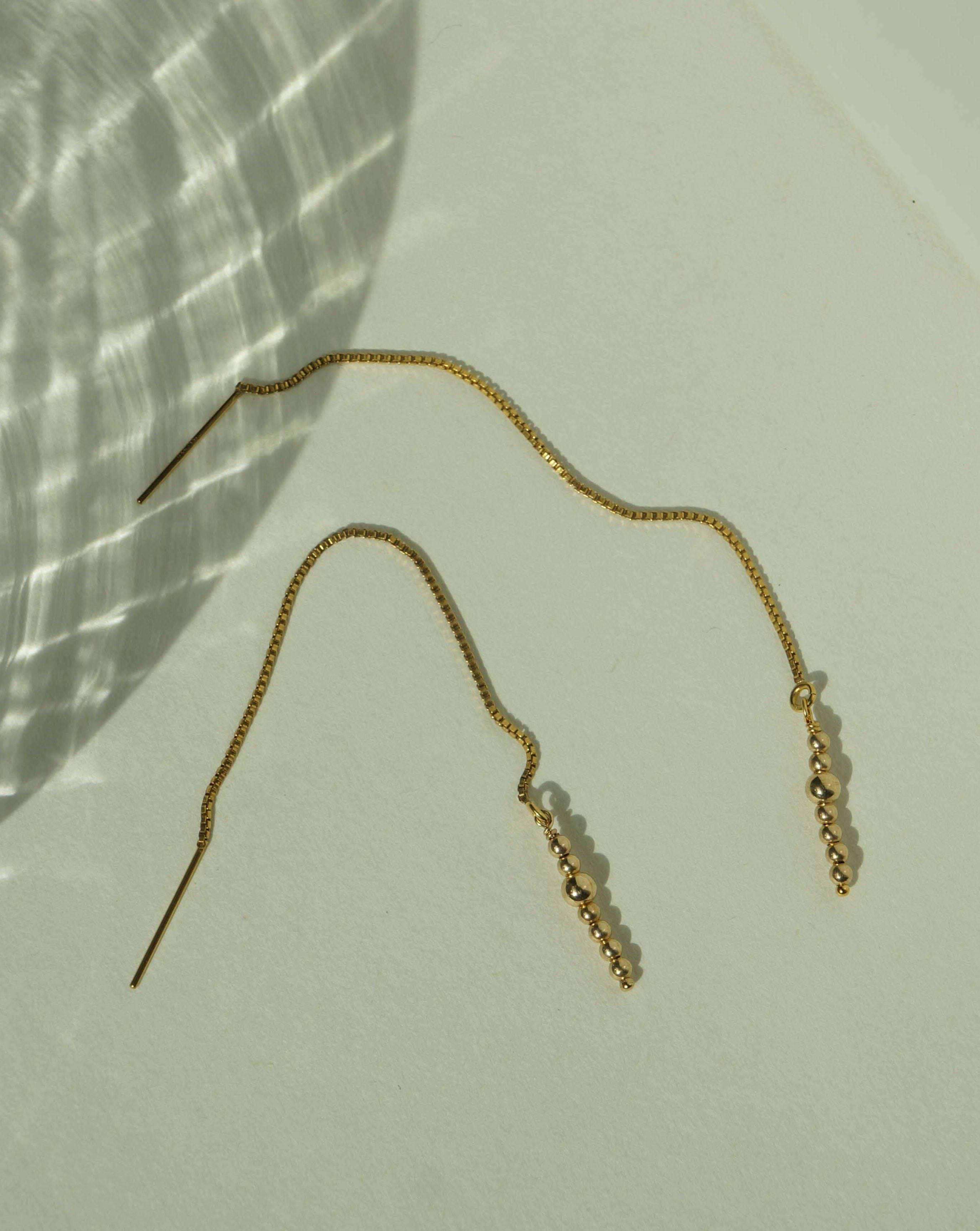 Lani Threader Earrings by KOZAKH. 1mm Box chain threader style earrings, crafted in 14K Gold Filled, featuring gold balls.