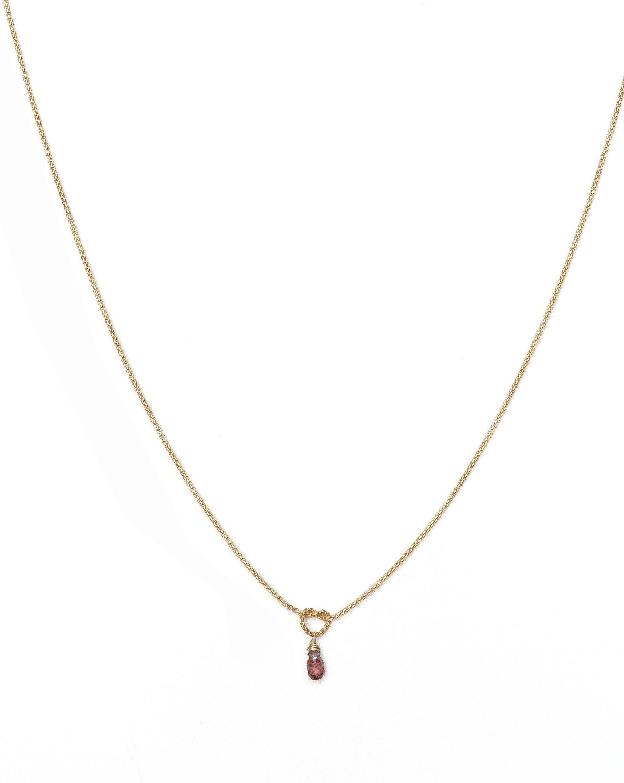 Love Knot Necklace by KOZAKH. A 16 to 18 inch adjustable length necklace, crafted in 14K Gold Filled, featuring a knot and a faceted Burgundy Sapphire droplet.