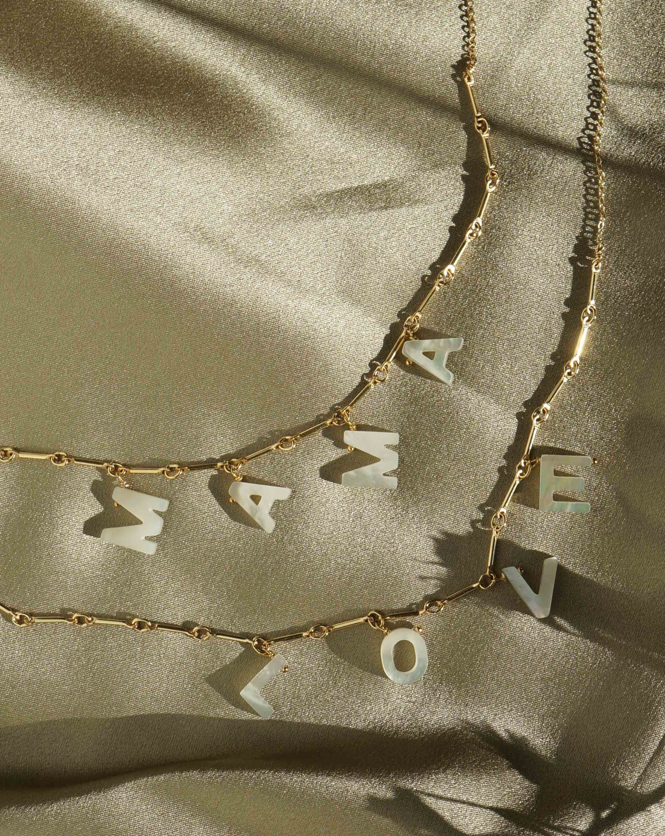 Love Necklace by KOZAKH. A 16 to 18 inch adjustable length necklace with linked bar chain on bottom half and flat link chain on top half, crafted in 14K Gold Filled, featuring a customizable word made from hand carved Mother of Pearl letters.
