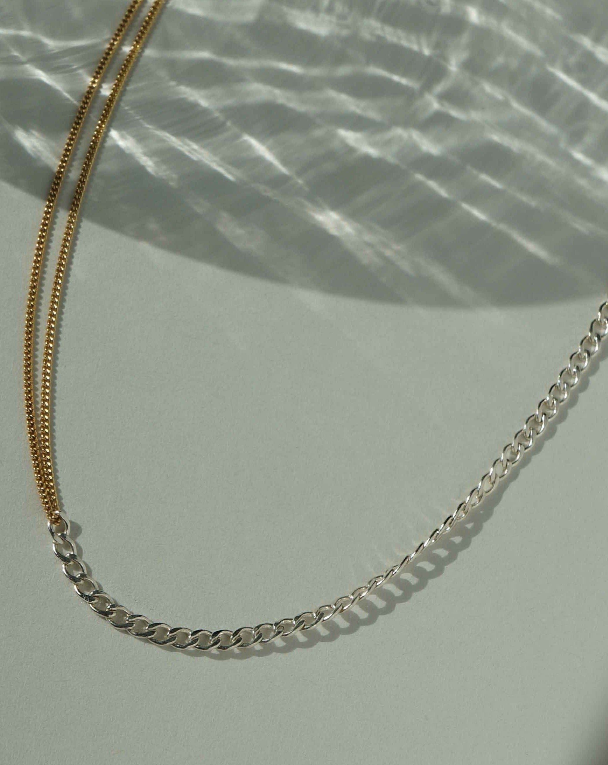 Monica Necklace by KOZAKH. A 14 to 16 inch adjustable length two tone necklace with gold box chain on one half and silver braided chain on the other half. 