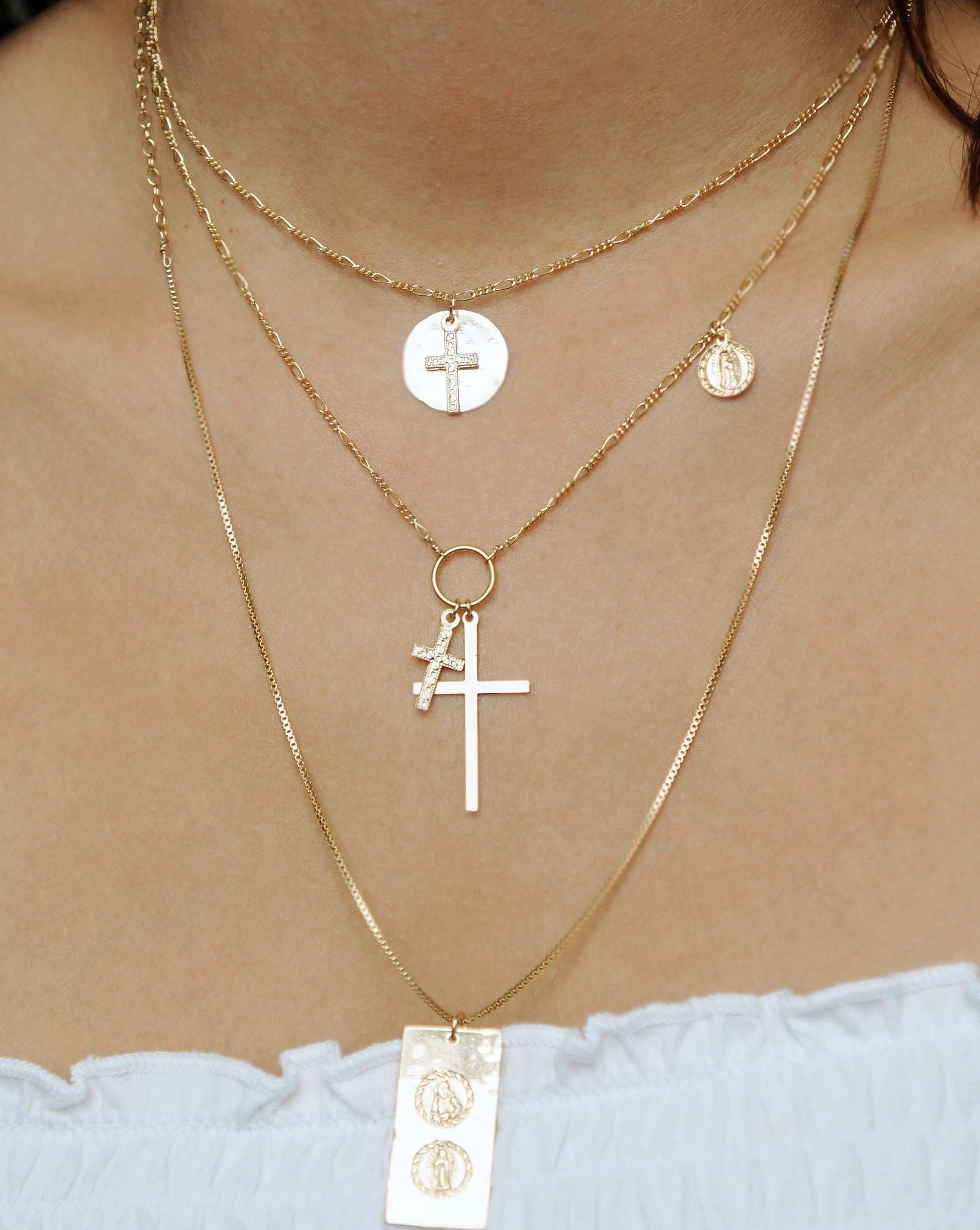 Orbis Necklace by KOZAKH. A 16 to 18 inch adjustable length Figaro chain necklace, crafted in 14K Gold Filled, featuring a 16mm Hammered on the sides coin and a 5x10mm Filigree cross.